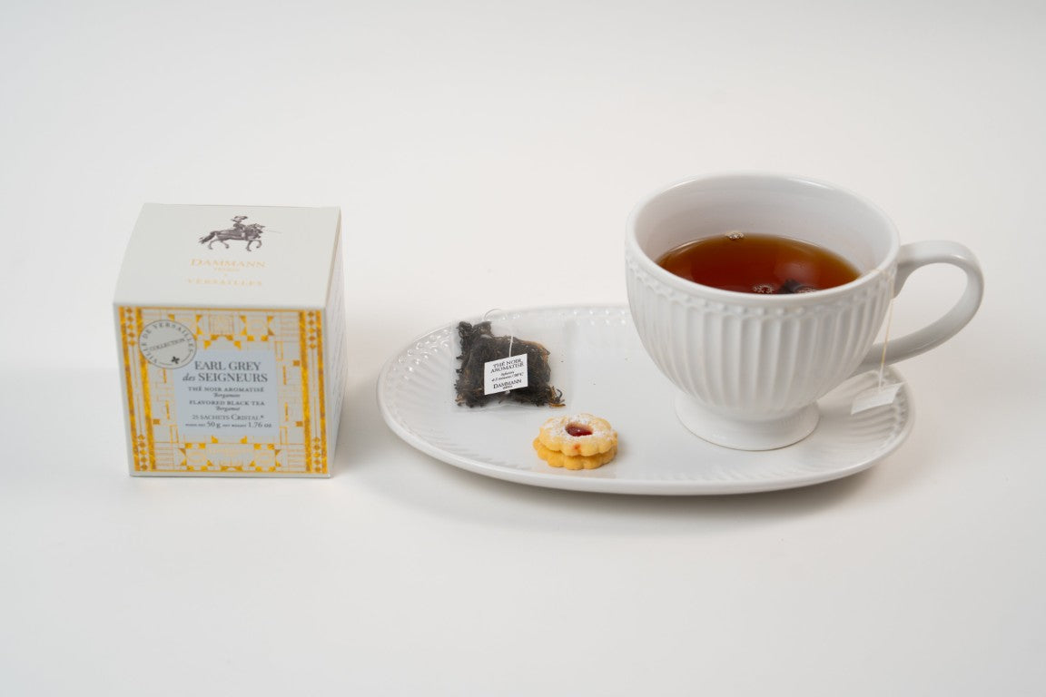 Dammann Frères Earl Grey des Seigneurs black tea with teacup, tea bag and biscuit on white plate