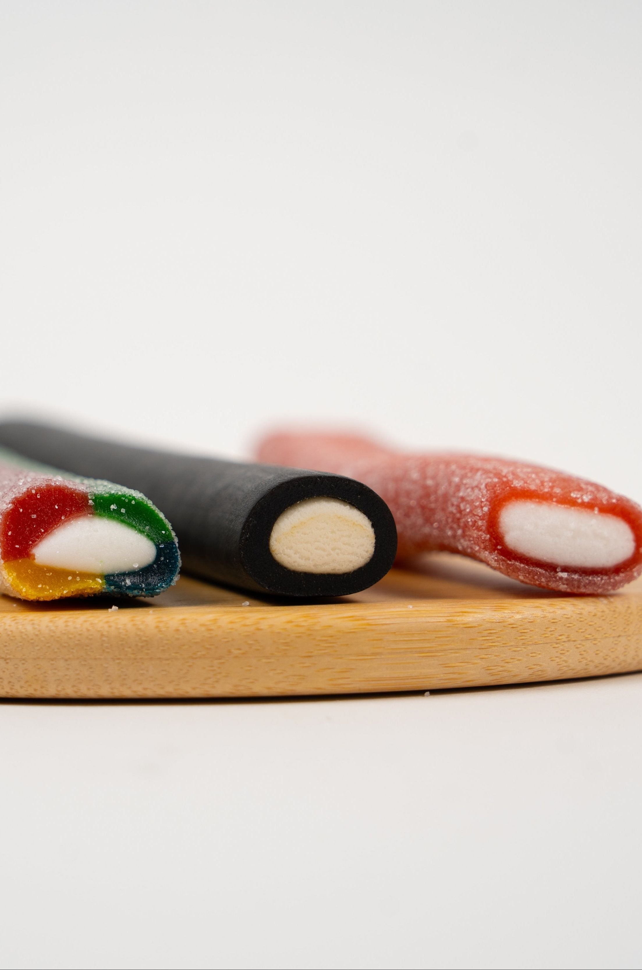 Bâton de réglisse artisanal acidulé saveur Tutti Frutti, confiserie colorée sur fond neutre.