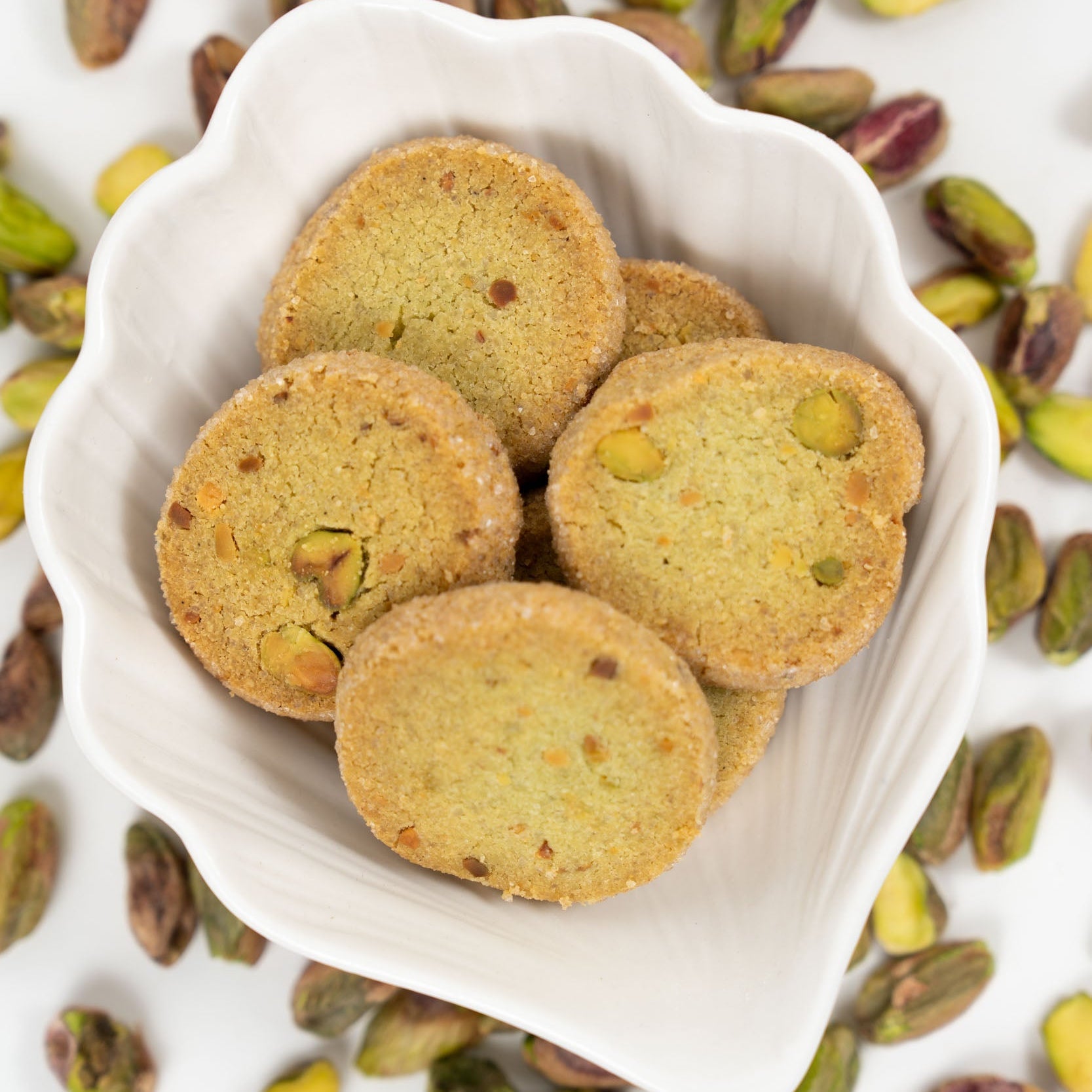 Biscuits sablés artisanaux à la pistache servis dans un bol blanc avec éclats de pistaches