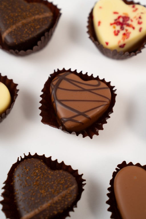 Gros plan sur un cœur truffe artisanal à la texture soyeuse et fondante.