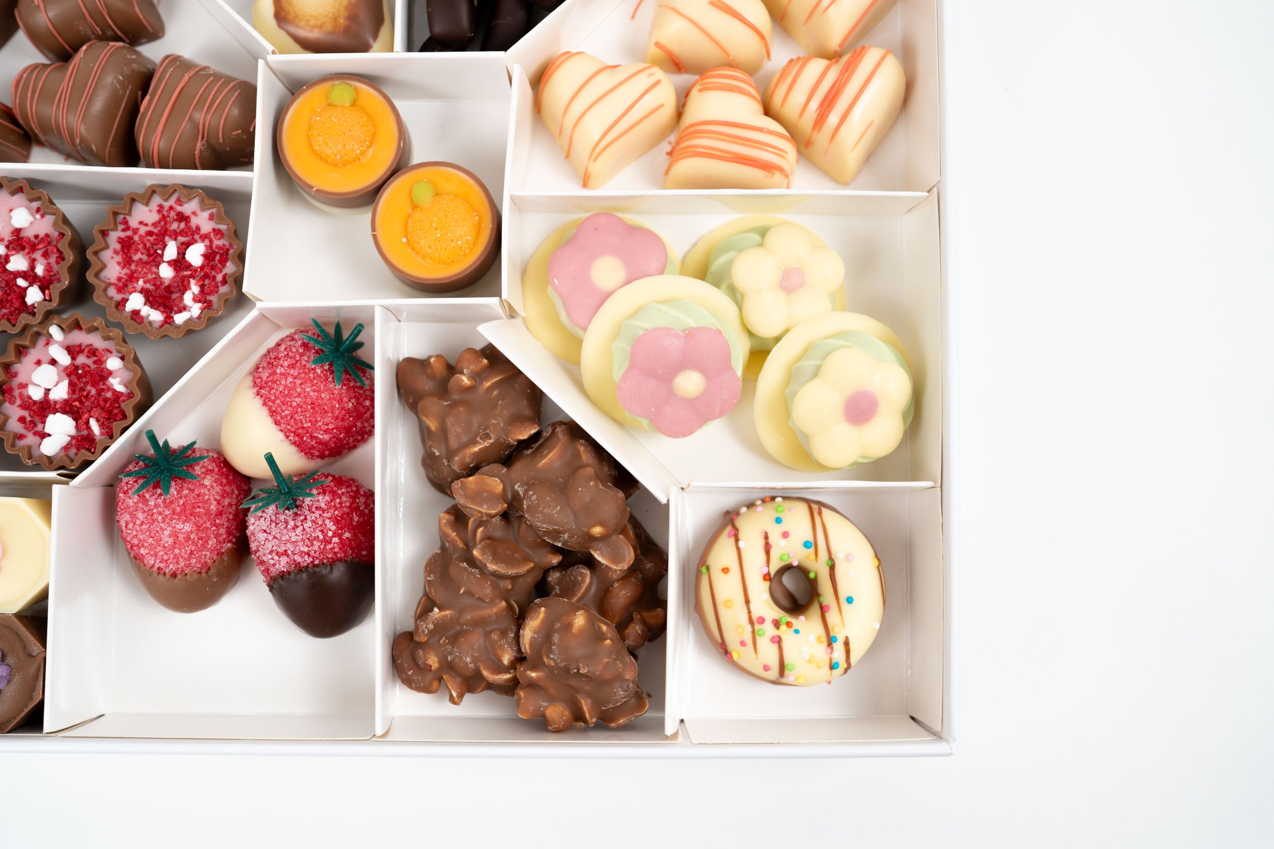 Détail de chocolats artisanaux décorés et confiseries dans une box gourmande