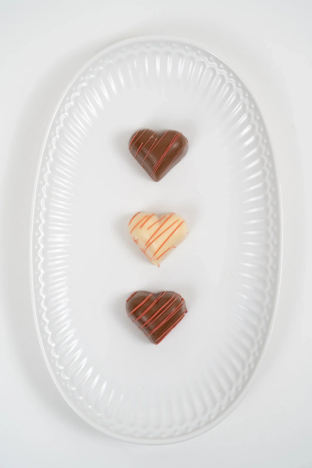 Filled milk and white chocolate hearts presented on a plate