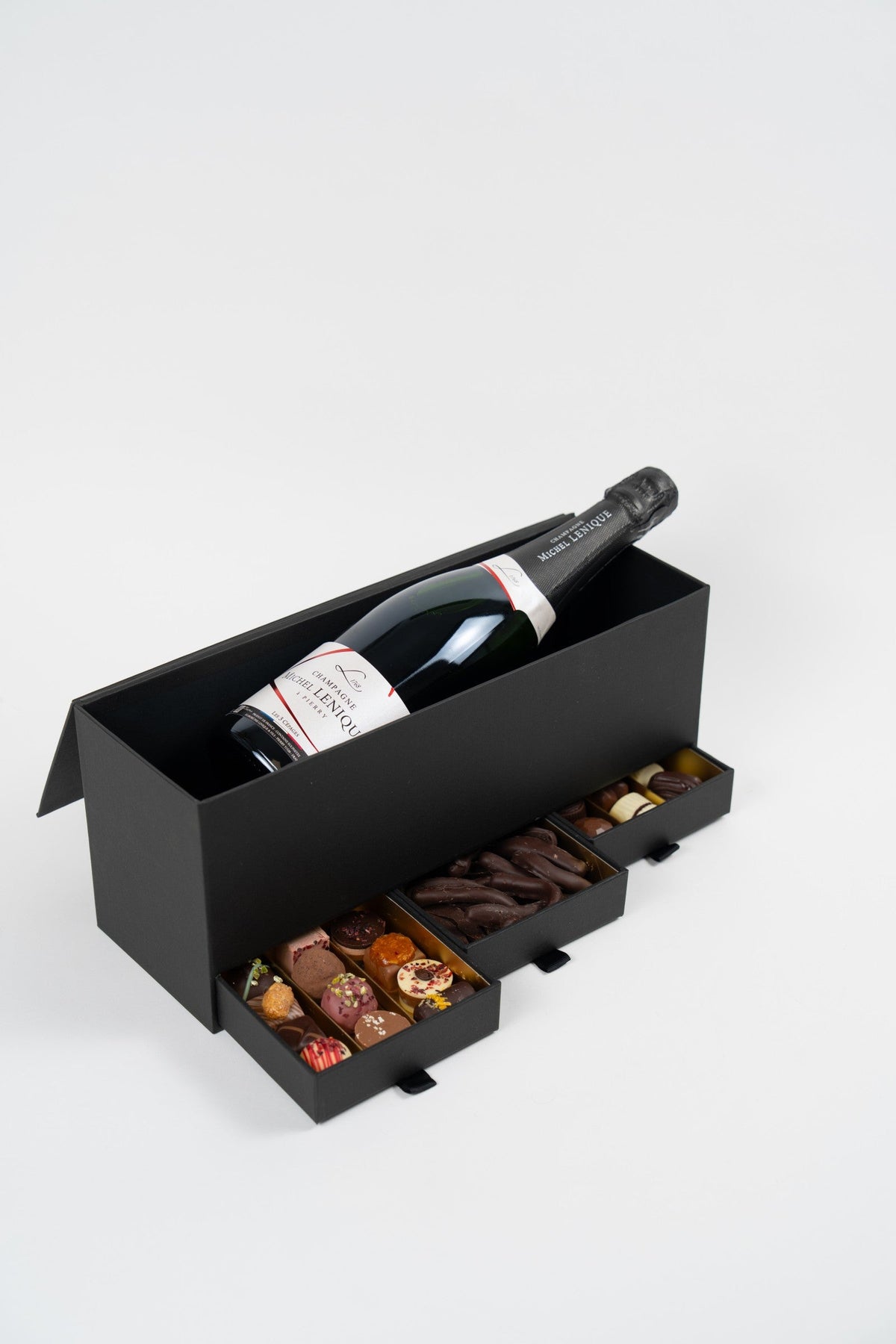 Coffret cadeau ouvert avec Champagne Michel Lenique et trois tiroirs de pralines artisanales assorties et d’orangettes