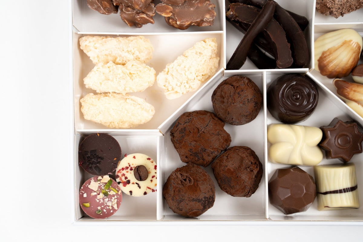 Dettaglio dei tartufi, dei cioccolatini decorati e delle scorze d’arancia candite ricoperte di cioccolato nel cofanetto