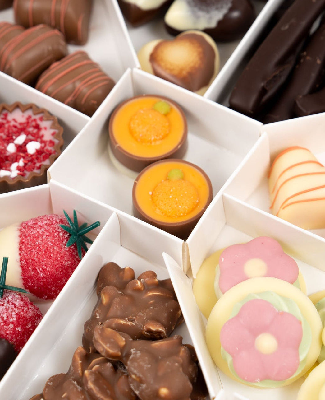 Coffret de chocolats de printemps artisanal avec assortiment de pralinés, fraises enrobées, orangettes et chocolats fourrés