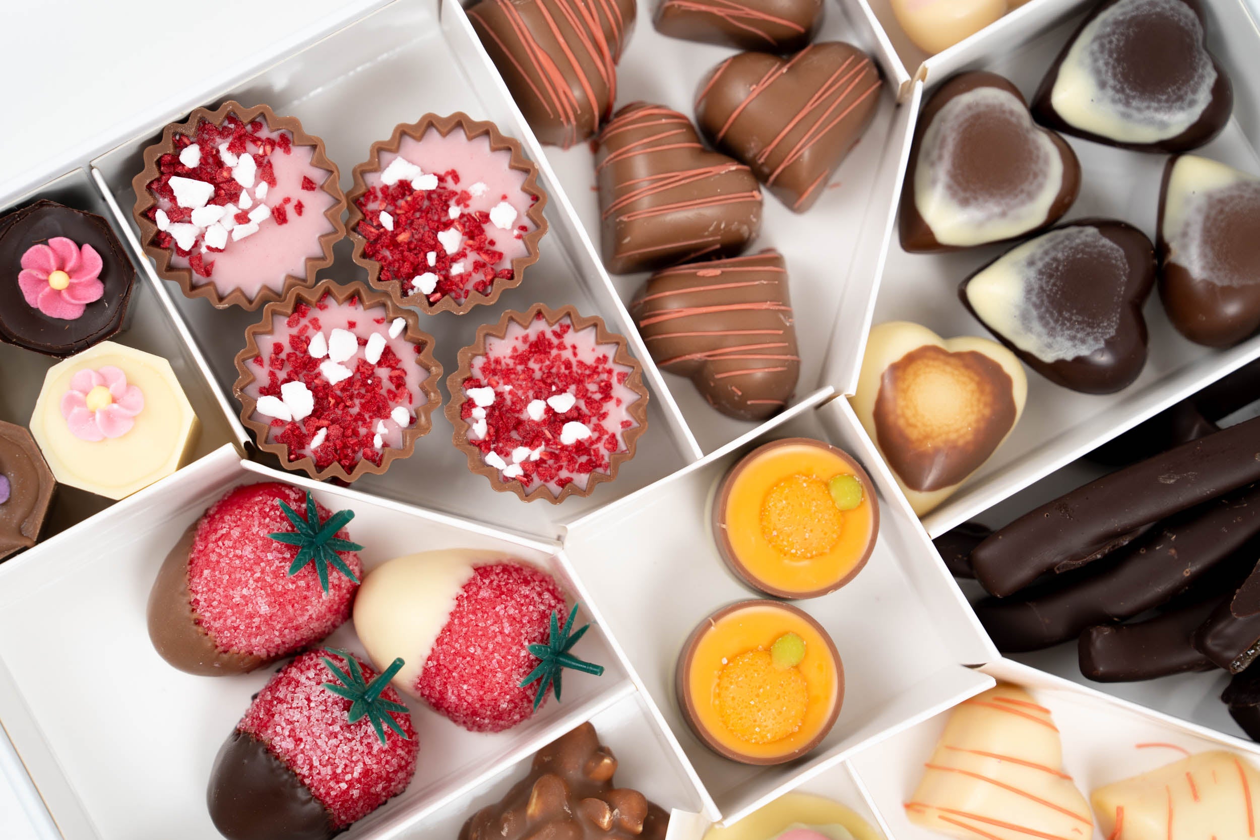 Coffret de chocolats de printemps artisanal avec assortiment de pralinés, fraises enrobées, orangettes et chocolats fourrés