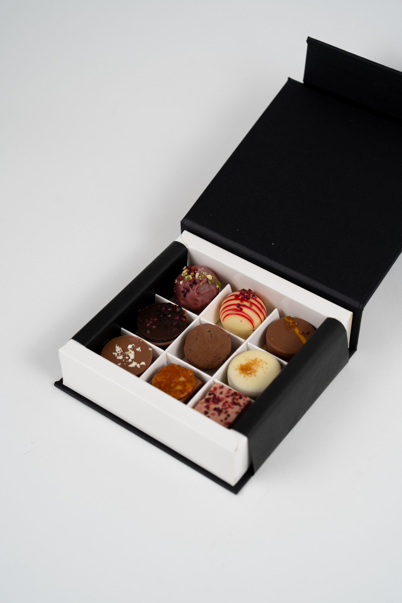 Coffret ouvert de pralines assorties présenté par Péché Mignon