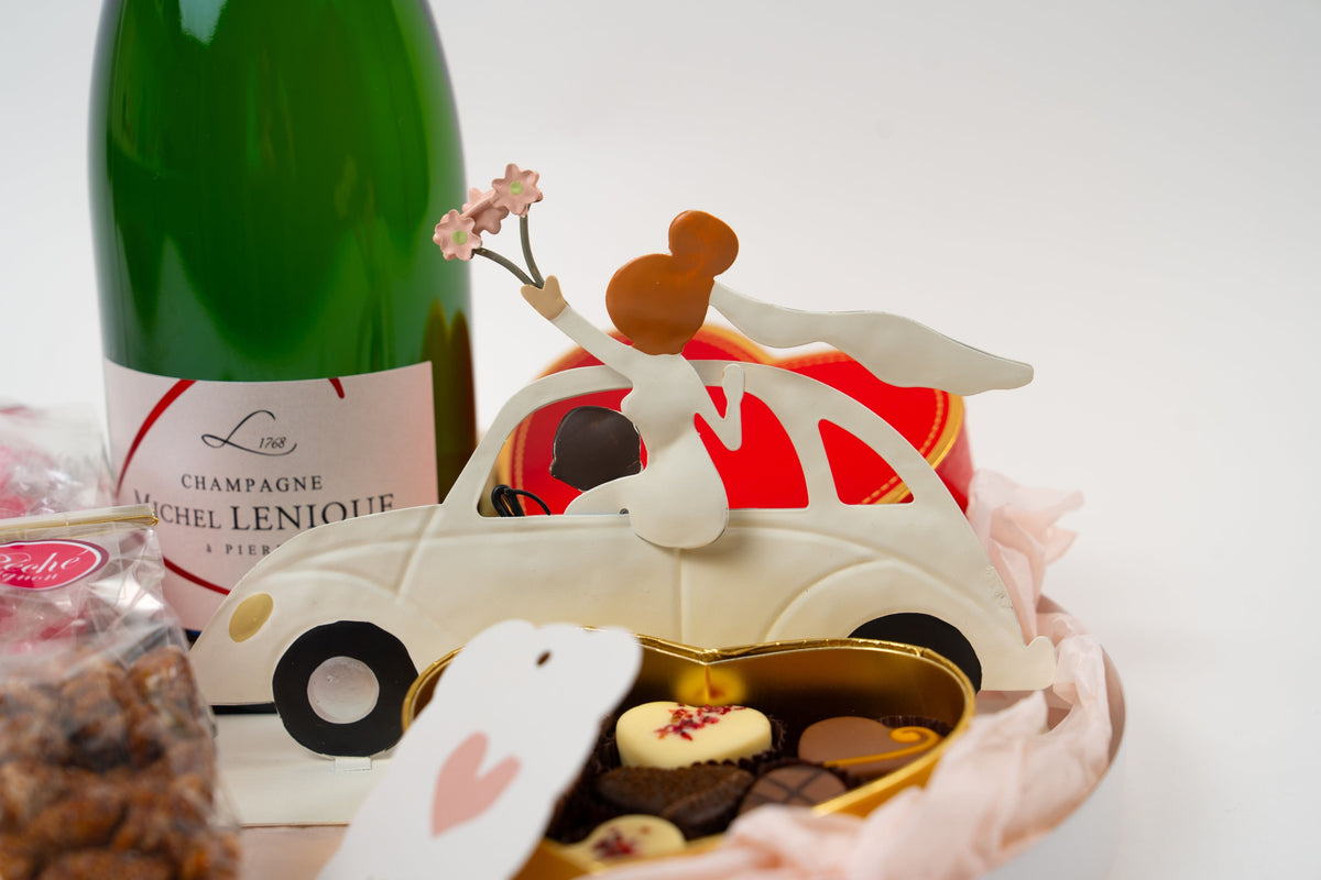 Detalle del cofre En Route vers l’Amour con champán, chocolates y coche nupcial decorativo
