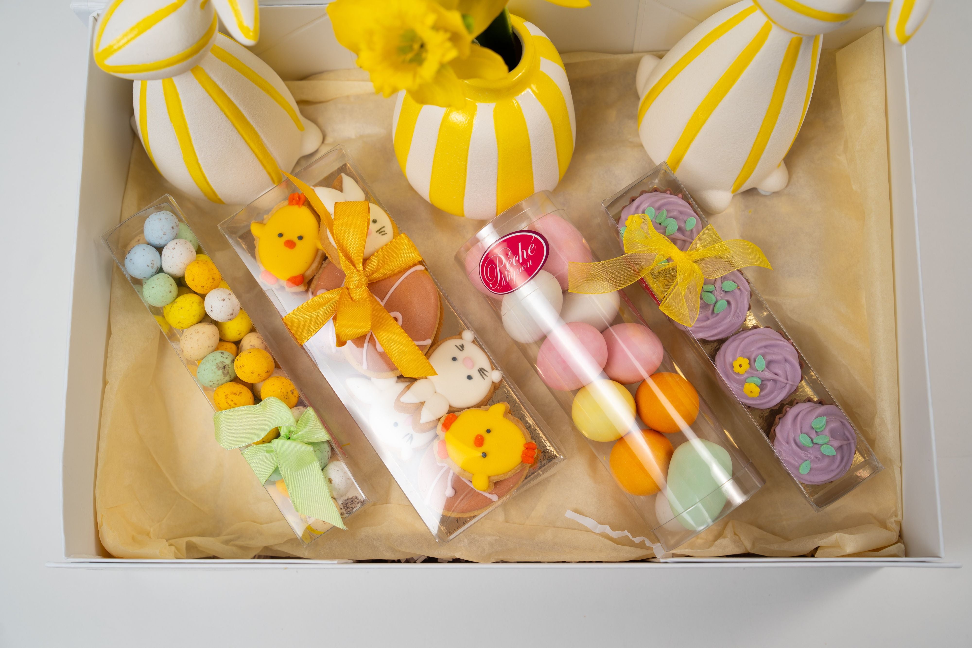 Easter sweets assortment with decorated cookies, chocolate eggs and pralines in a Péché Mignon gift box.
