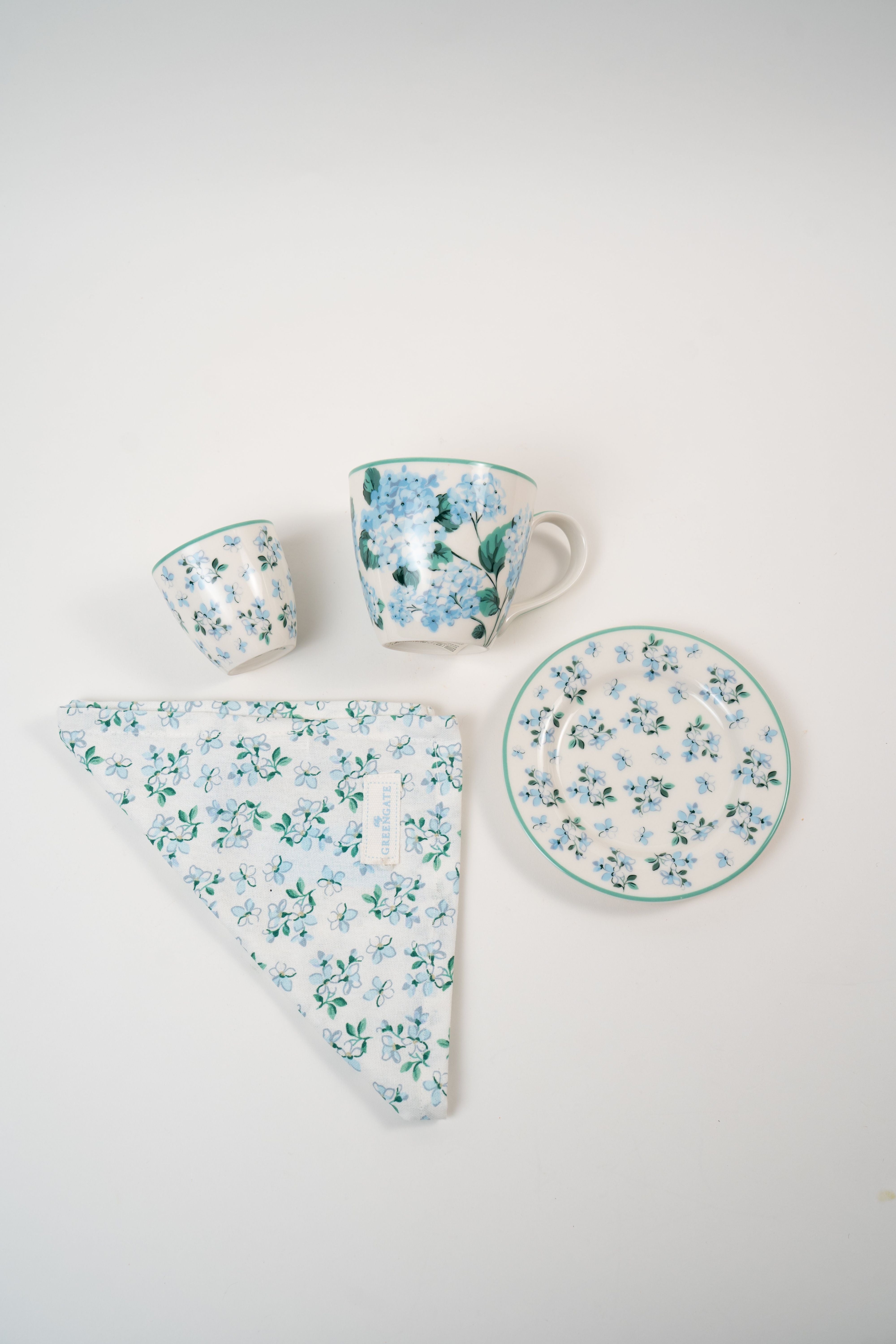 GreenGate Liliana floral tableware collection featuring a ceramic mug, espresso cup, plate and matching floral napkin in soft blue tones