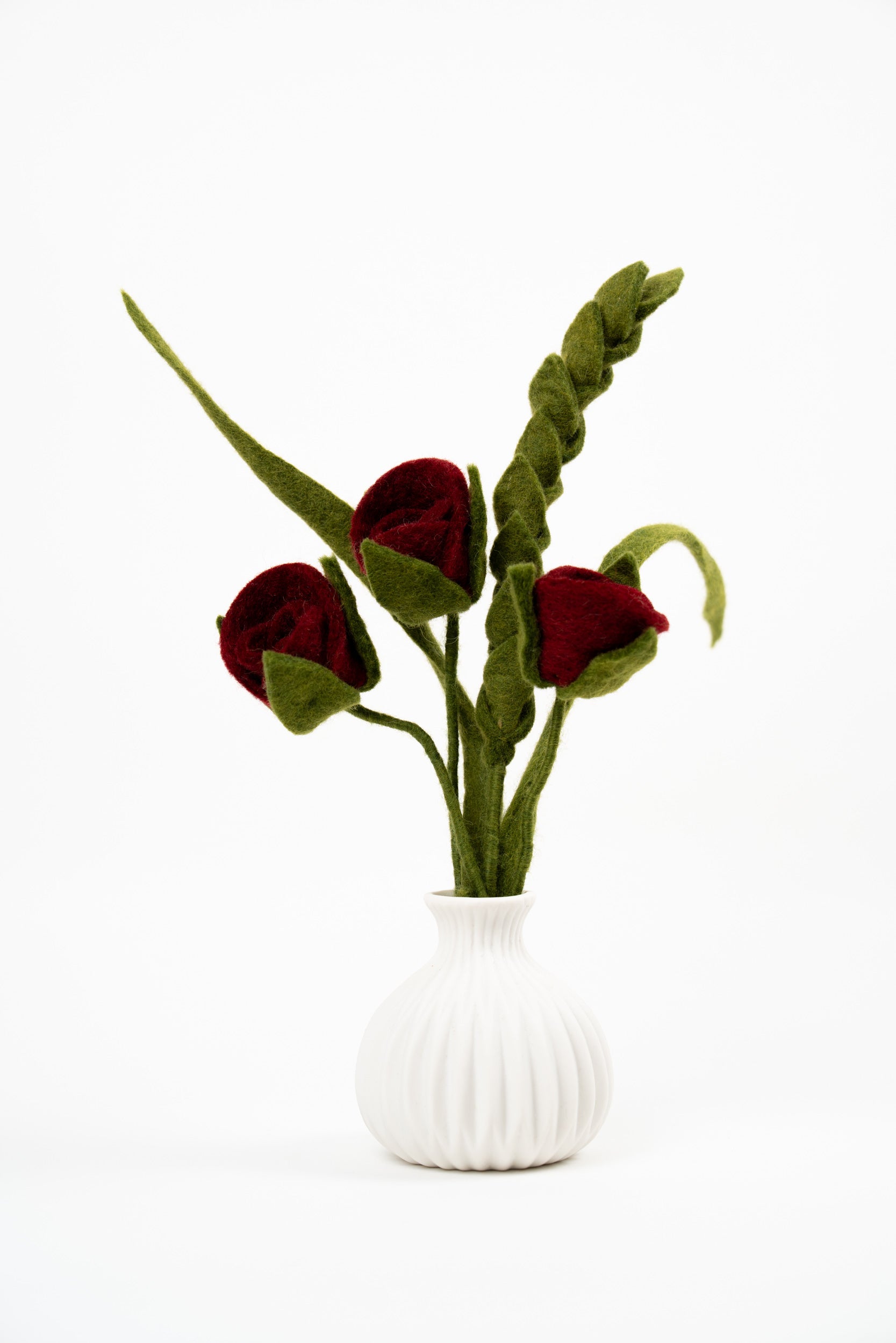 Handmade Gry & Sif felt bouquet with three red roses and green leaves displayed in a white ceramic vase