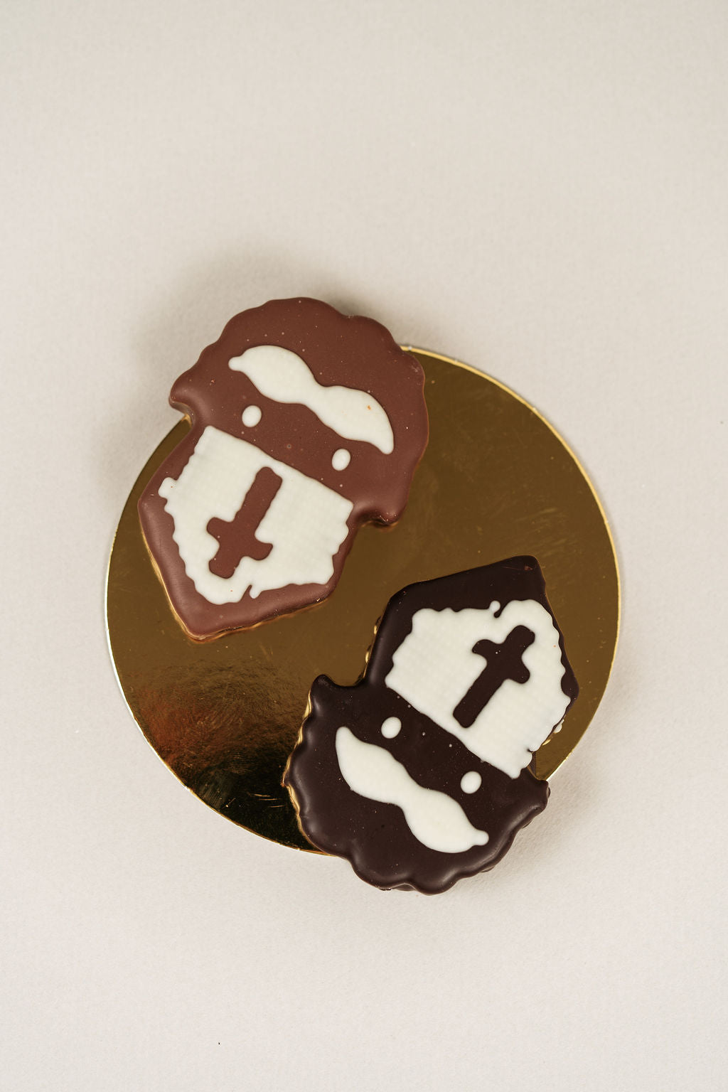 Deux guimauves artisanales Saint-Nicolas enrobées de chocolat au lait et de chocolat noir, présentées sur un support doré.
