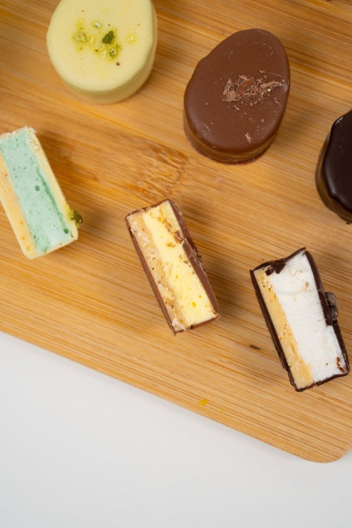 assortiment de guimauves style Dubaï enrobées de chocolat avec pistache et kadayif sur planche en bois