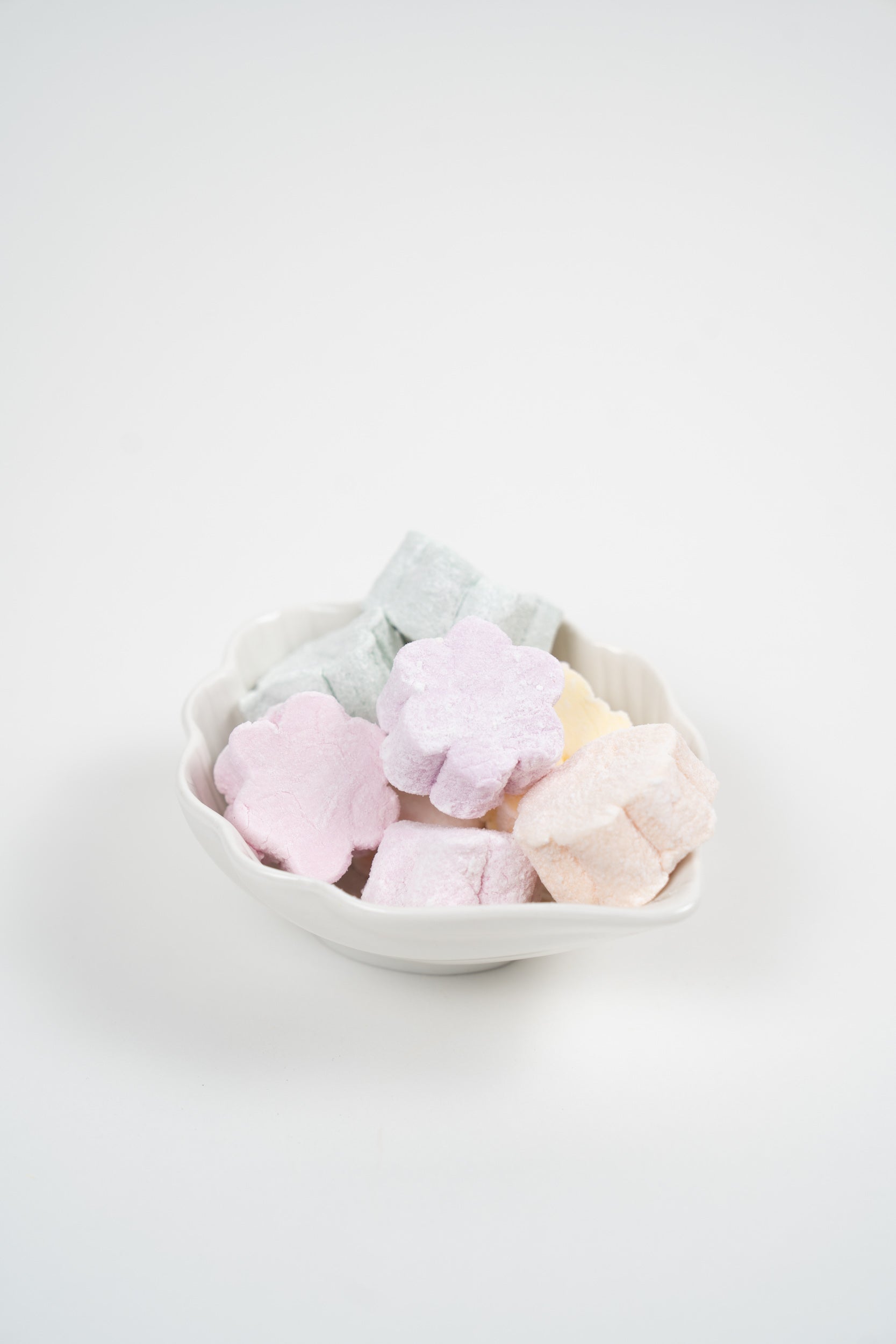 Assorted mini marshmallows in flower shapes, soft pastel colours in a white bowl
