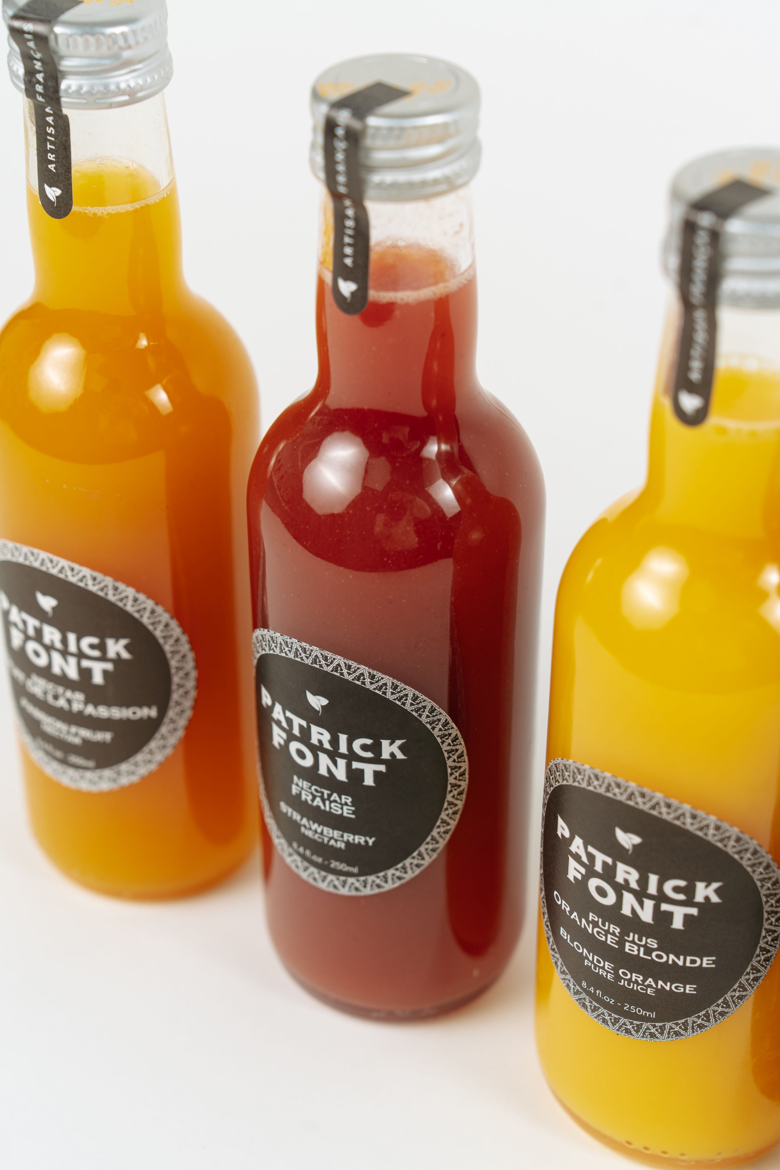 Assortiment de nectars de fruits Patrick Font en bouteilles.