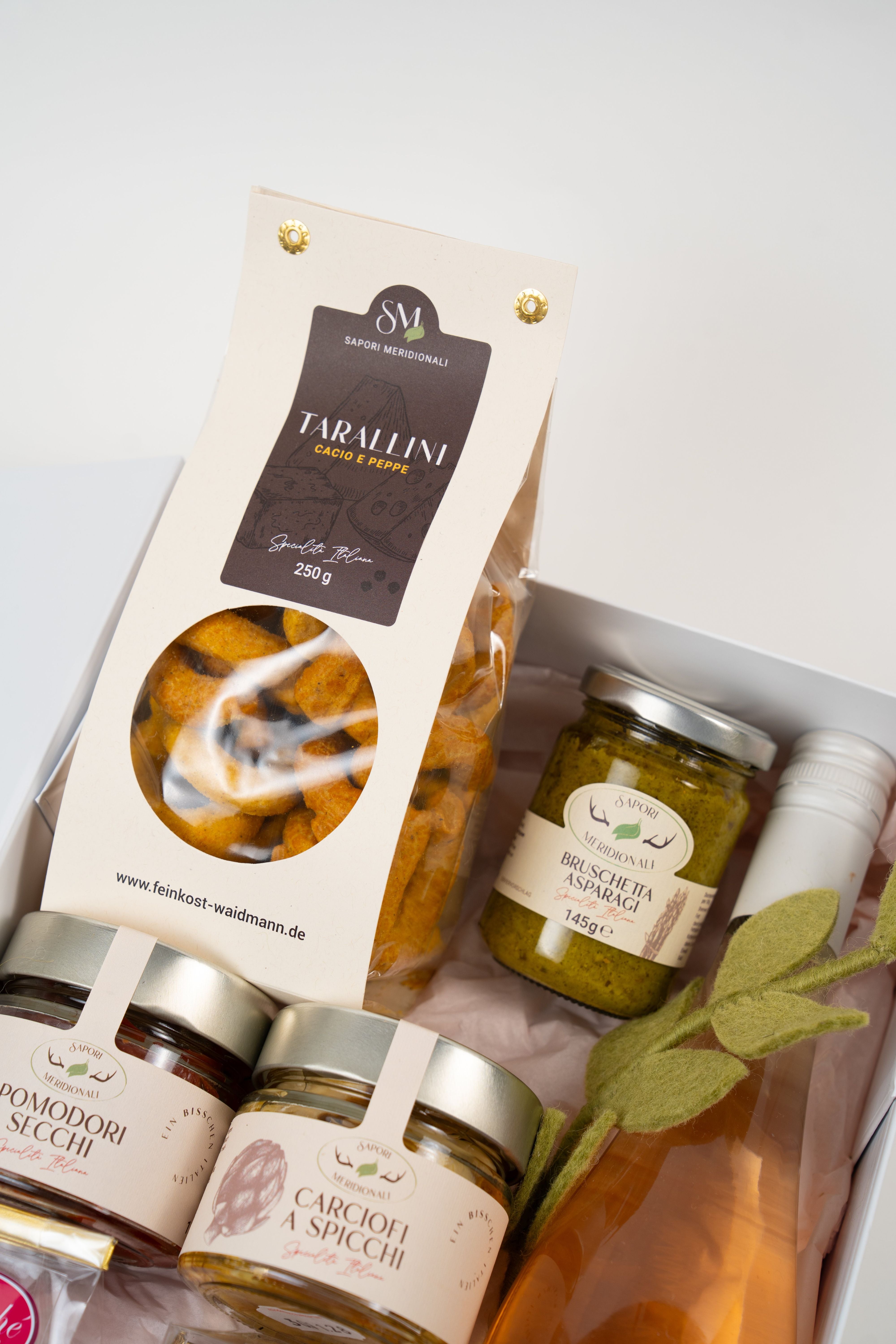 Close-up of Le Péché Mignon gourmet gift box with antipasti jars, caramel candies and roasted nuts