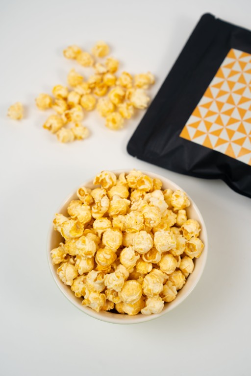 Gros plan sur du popcorn artisanal à la noix de coco et fruit de la passion (maracuja). Grains parsemés de copeaux de coco.