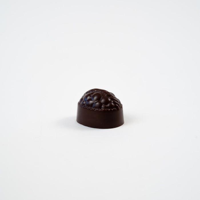Artisan Belgian Lady praline in dark chocolate with raspberry fondant, on a white background.