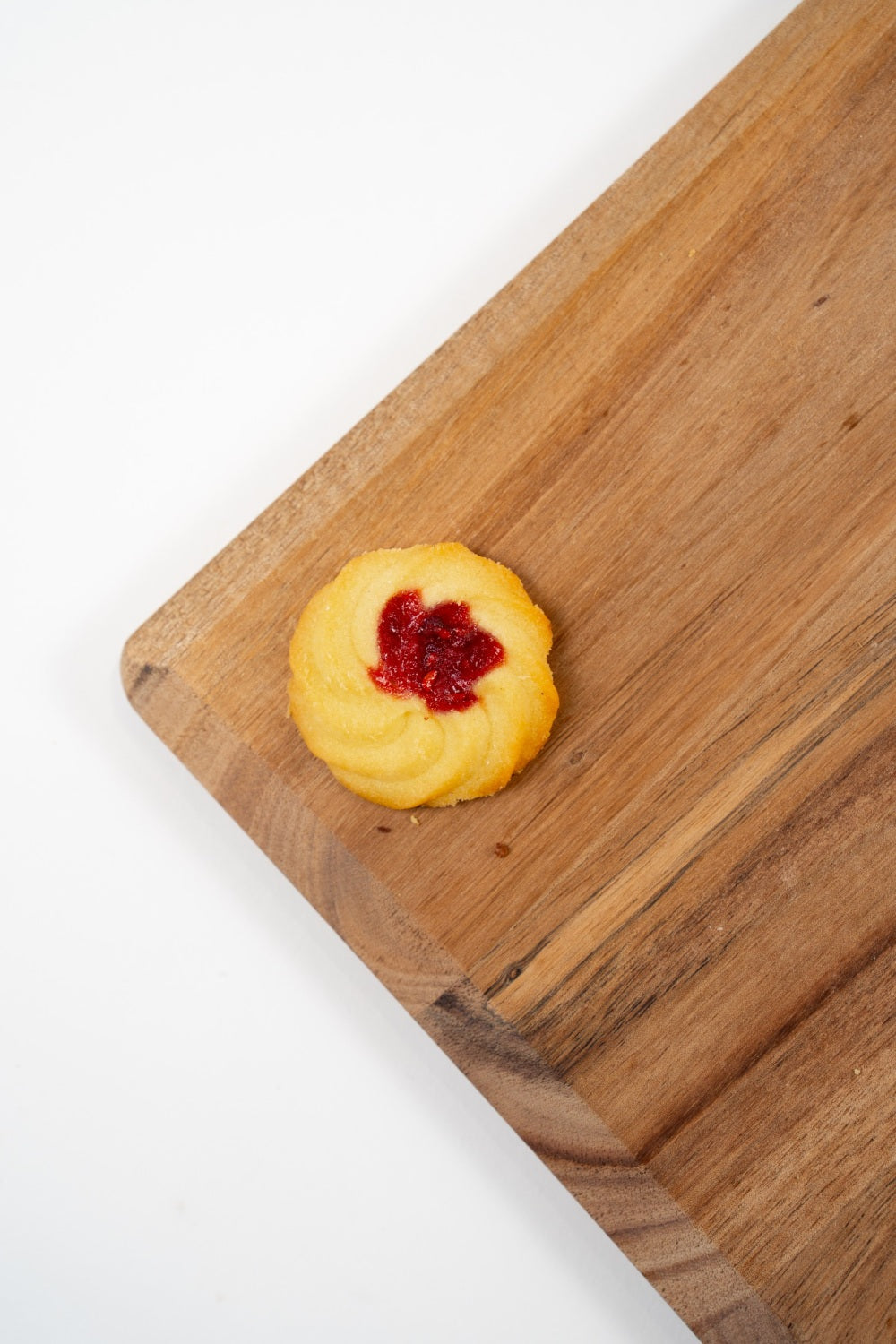 Rosette Framboise, biscuit au beurre garni d’un cœur à la framboise, présentée sur une planche en bois.