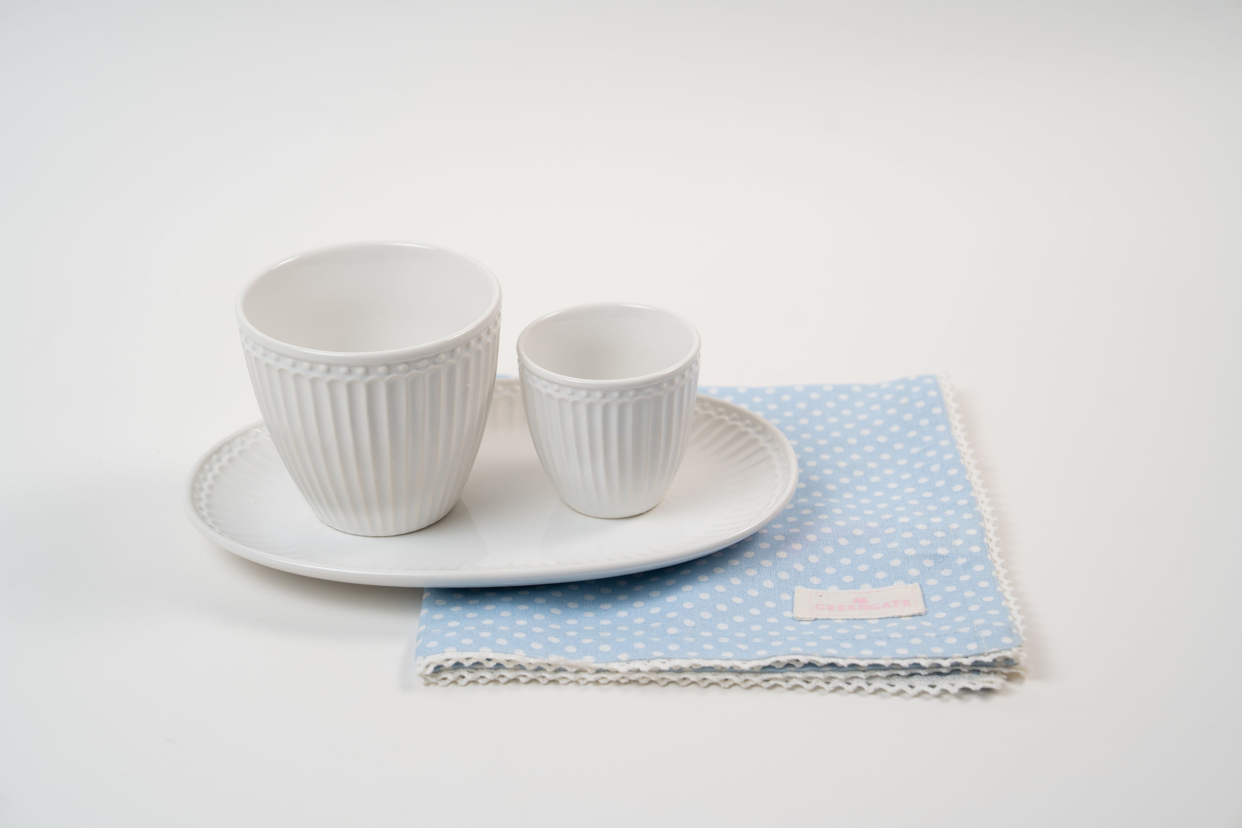 Tasses en porcelaine blanche côtelées pour thé et expresso sur plateau avec serviette bleue