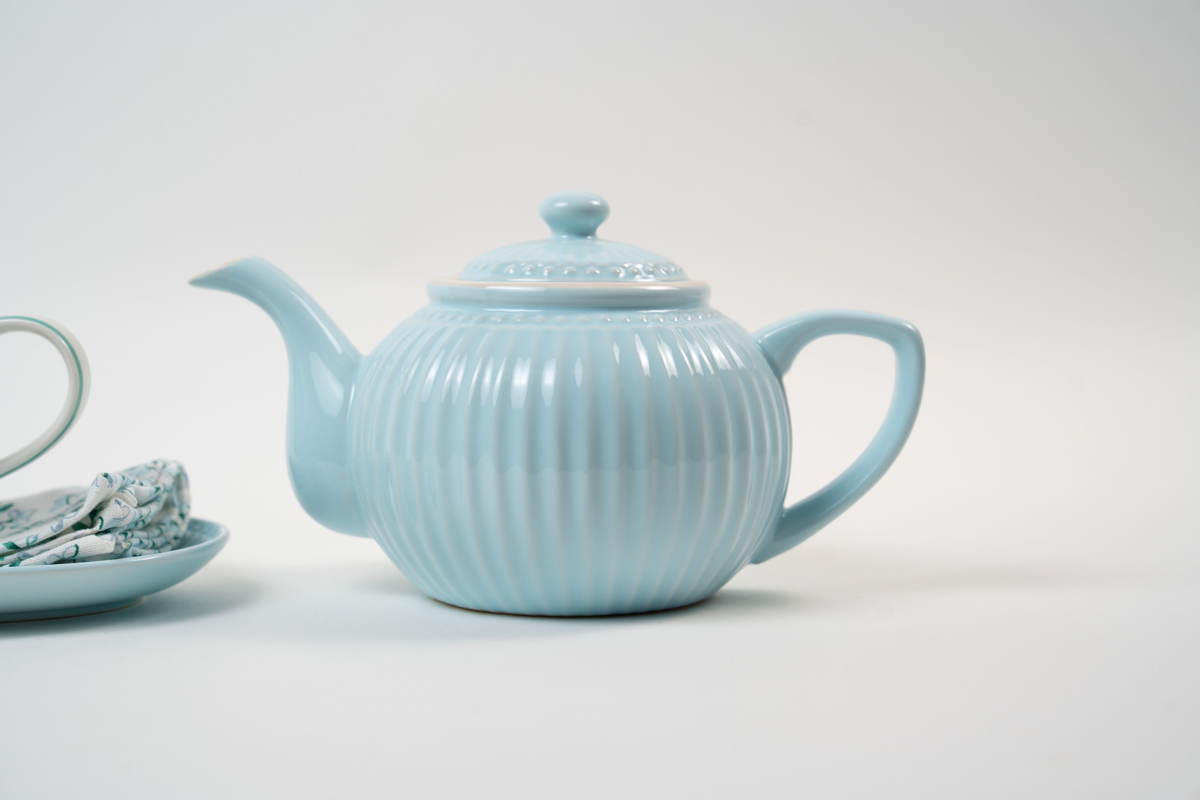 Théière en céramique bleu pastel au design délicatement nervuré et aux finitions élégantes. Une pièce intemporelle qui apporte une touche de douceur et de raffinement à votre table.