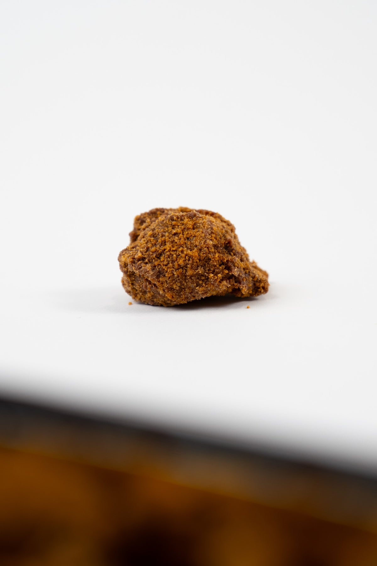 Truffe au spéculoos Péché Mignon enrobée d’éclats de biscuit, présentée seule sur fond blanc.