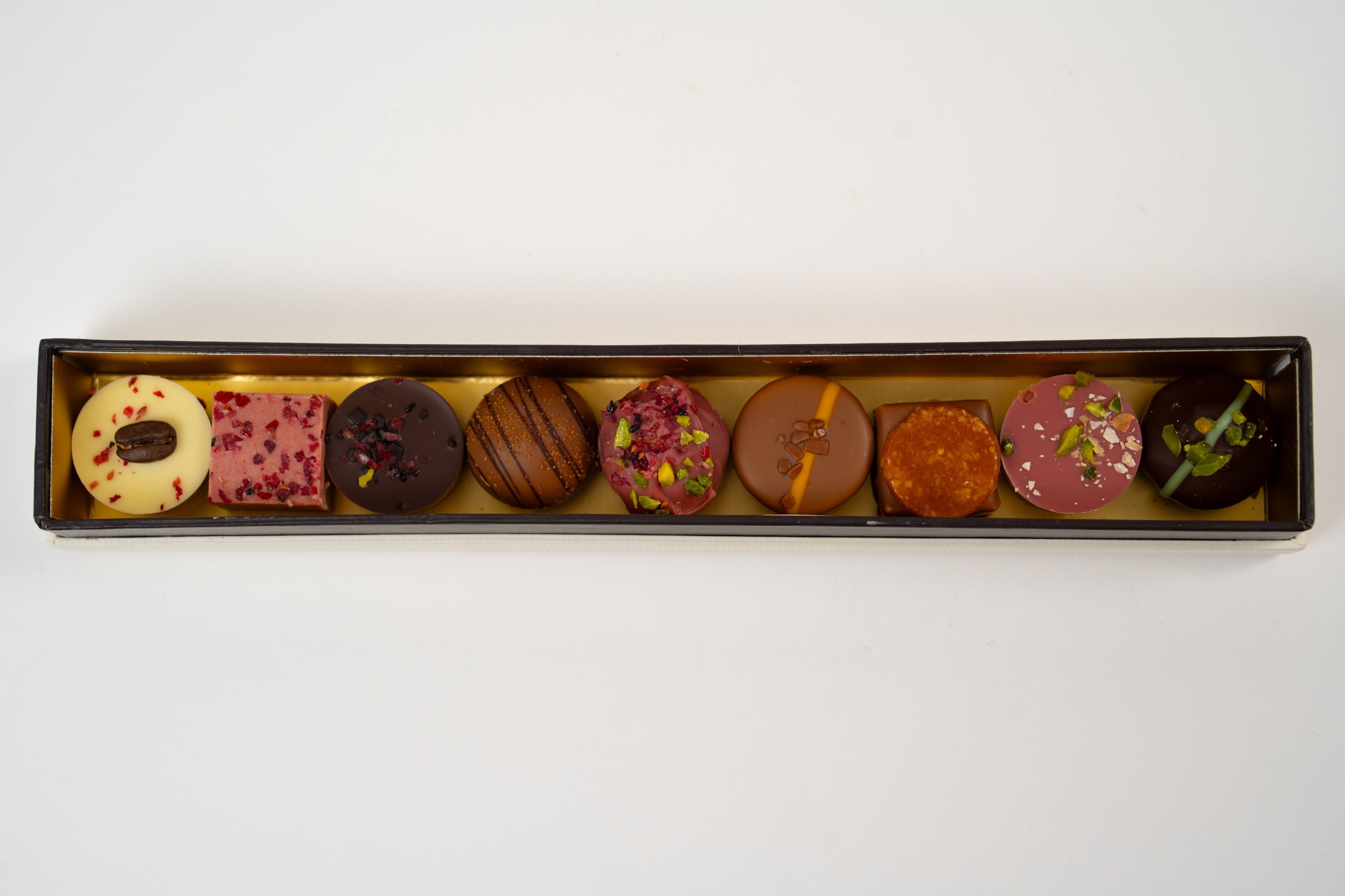 Luxury assortment of handcrafted pralines including pistachio, caramel, raspberry and coffee chocolates