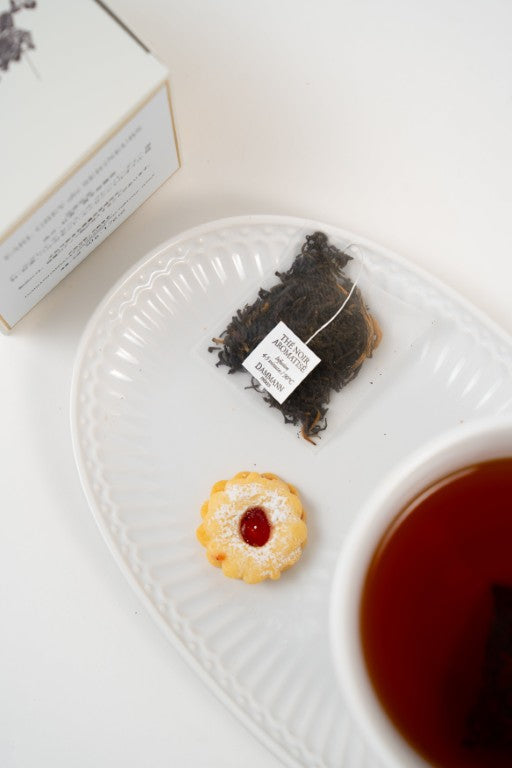 Earl Grey tea bag with bergamot served with tea and biscuit on white plate