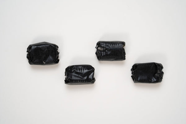 Traditional artisan black liquorice candies with a soft chewy texture displayed on a white background