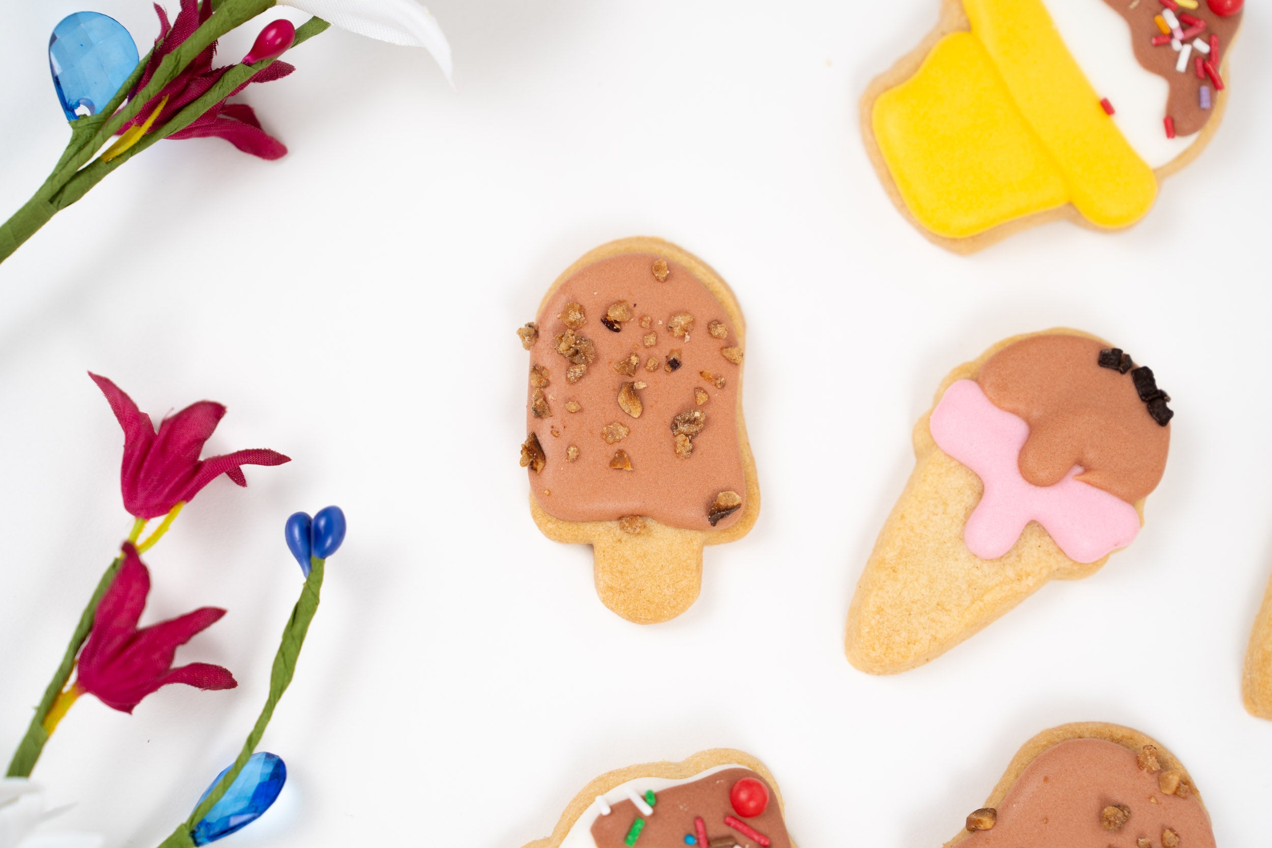Assortment of hand-decorated biscuits with ice cream designs and chocolate icing on white background