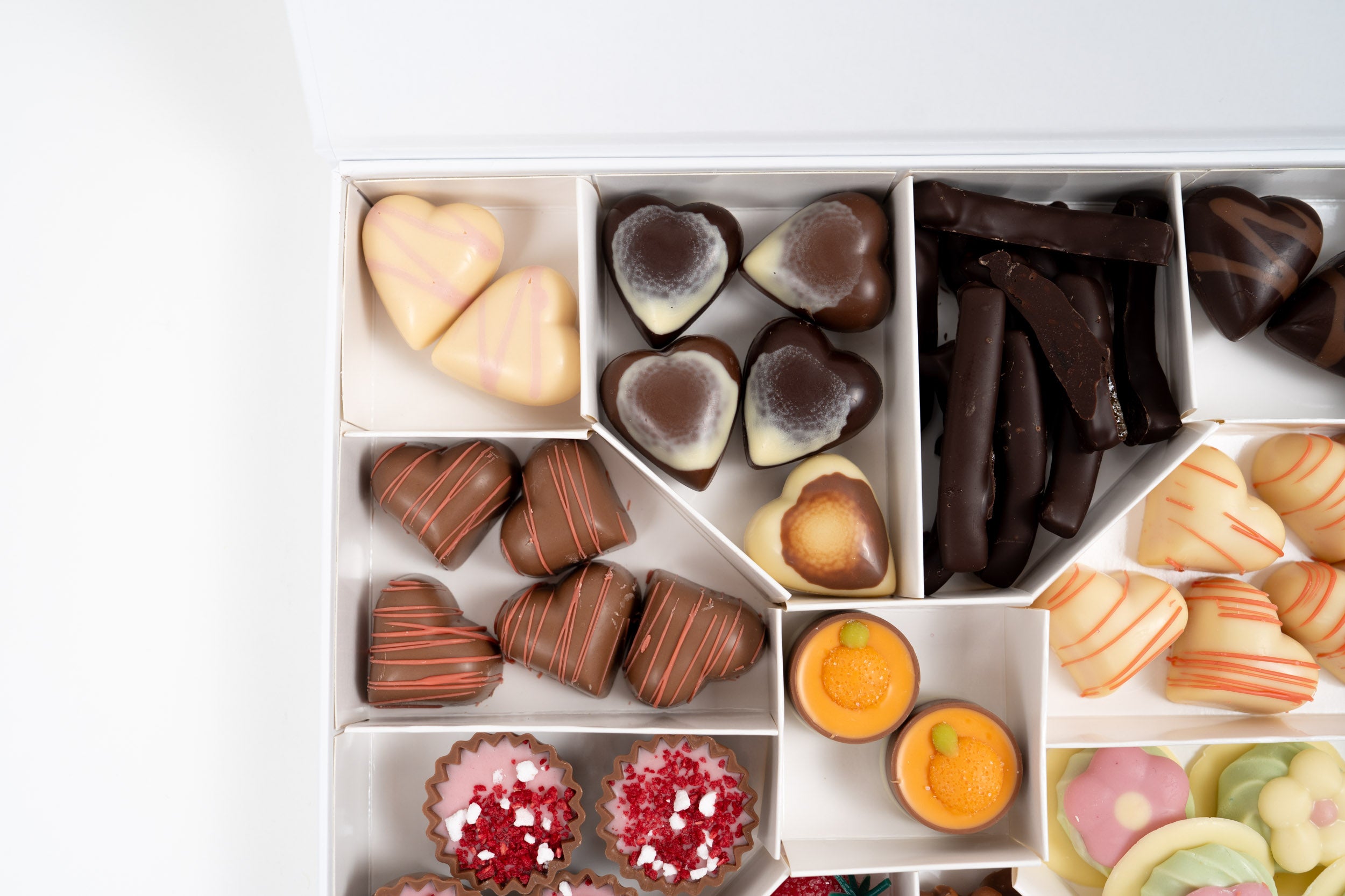 Détail d’un assortiment de chocolats artisanaux avec pralinés, ganaches fruitées et douceurs chocolatées premium