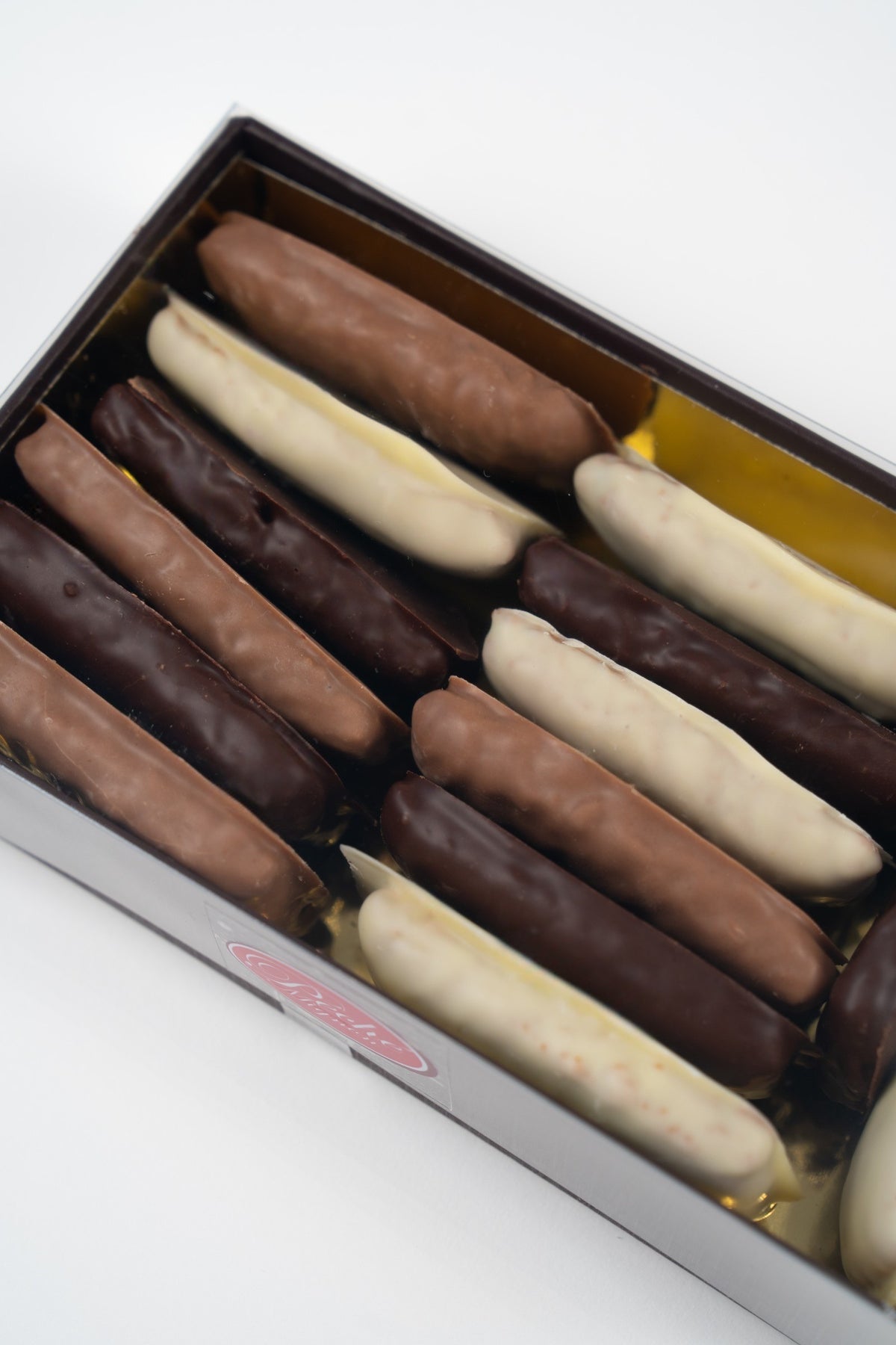 Close-up van Weichprinten met pure, melk- en witte chocolade in een geschenkdoos van Péché Mignon.