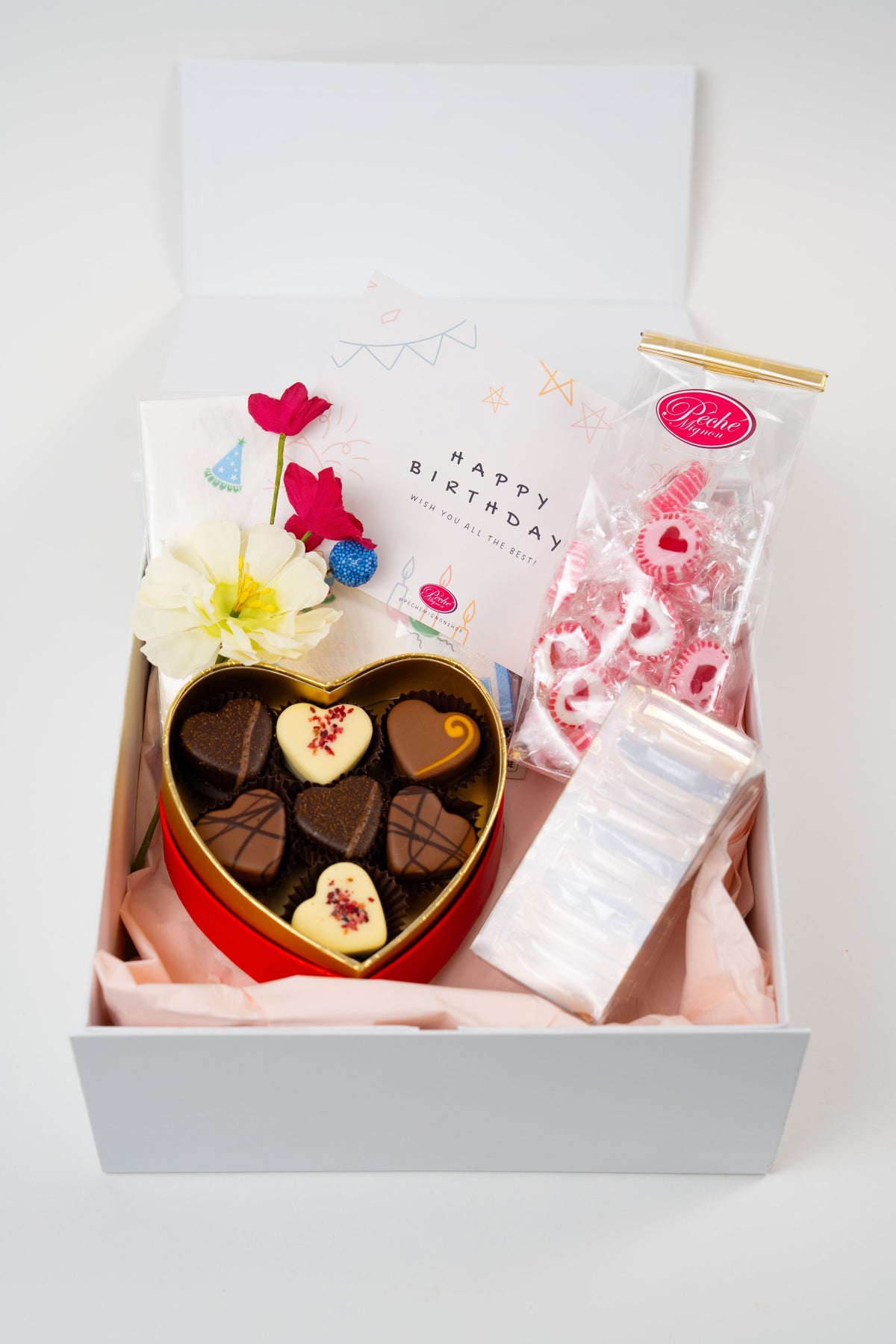 Birthday chocolate gift box from Péché Mignon with heart pralines, gourmet caramels and strawberry heart candies.