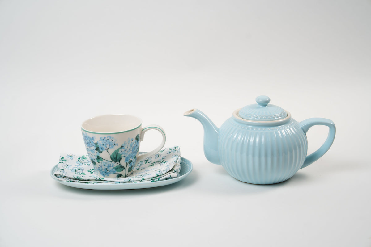 Service à thé raffiné composé d’une théière en céramique bleu pastel nervurée, accompagné d’une tasse fleurie avec soucoupe et serviette assortie. Une harmonie douce et élégante pour sublimer vos moments de dégustation.
