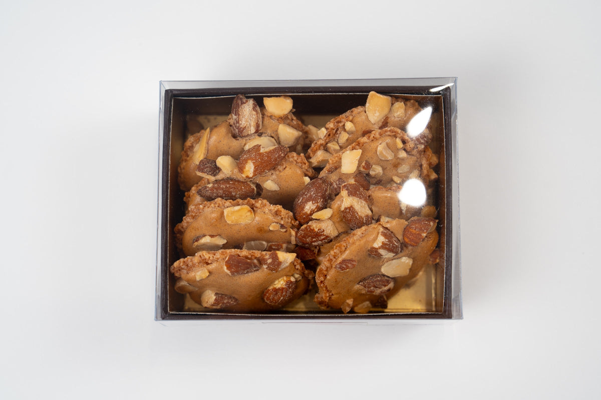 Caja de ocho merengues belgas de almendra con tapa transparente sobre fondo blanco.
