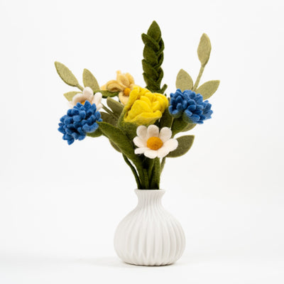 Petit bouquet de fleurs colorées en feutrine dans un vase blanc décoratif au style artisanal et élégant.