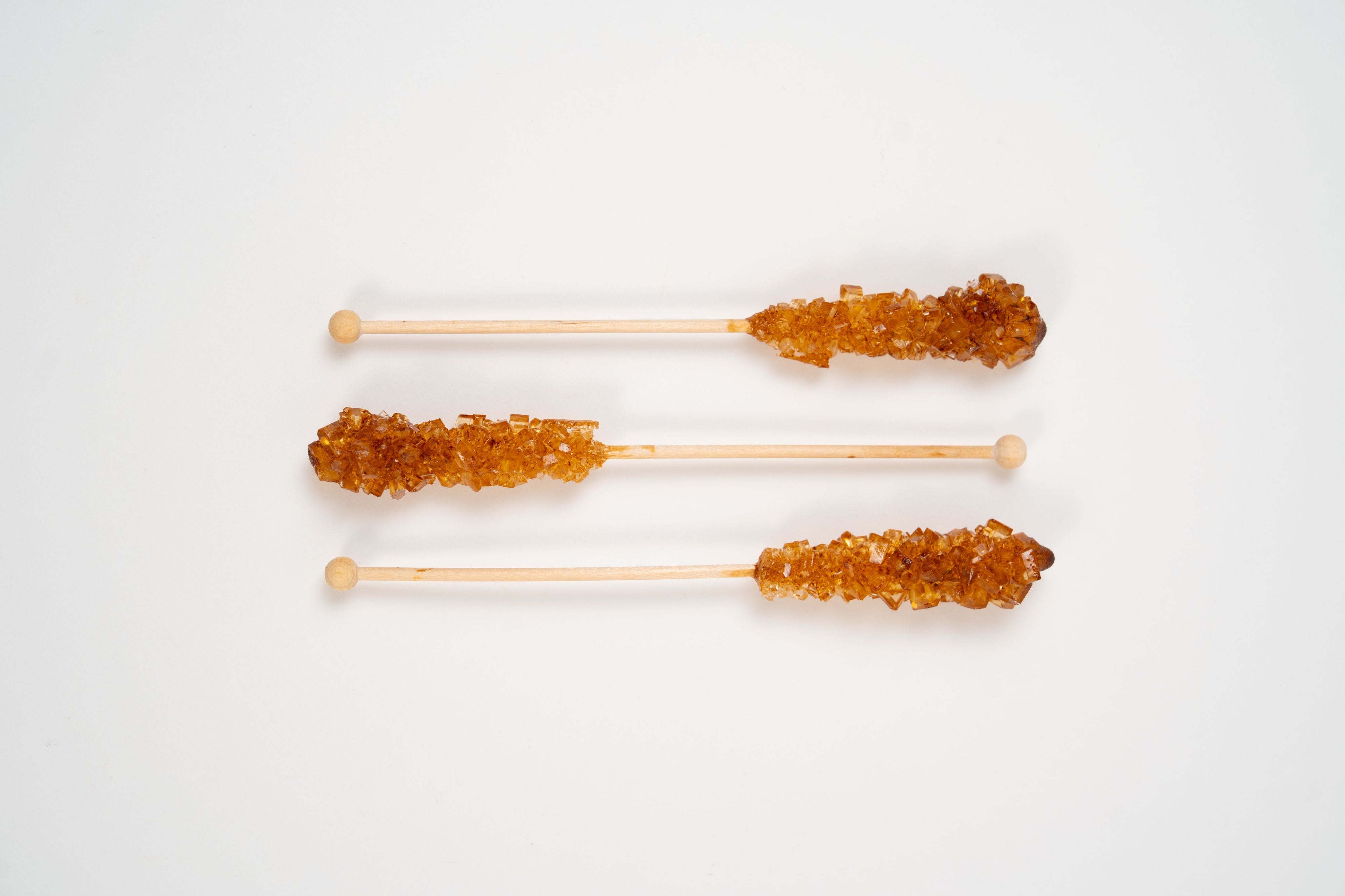Brauner kandis brown rock sugar crystals on wooden sticks for tea sweetener