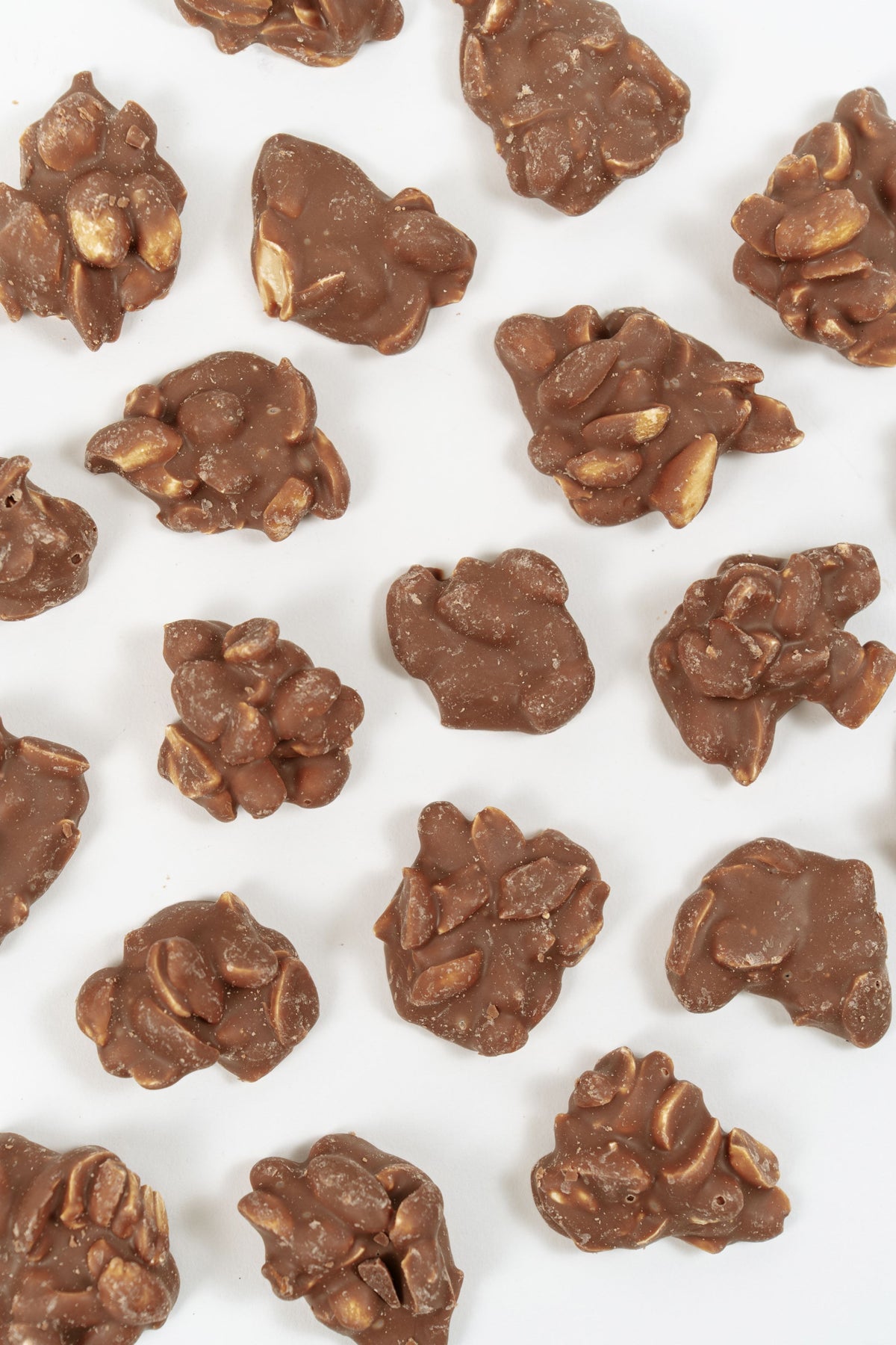 Cacahuètes enrobées de chocolat au lait disposées sur fond clair, vue du dessus