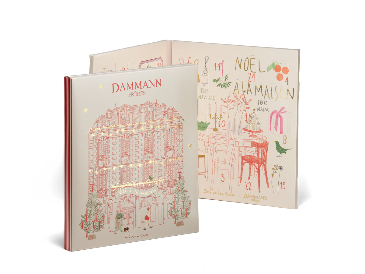 Calendrier de l’Avent Dammann Frères 2026 présenté fermé et ouvert, avec une façade parisienne illustrée sur la couverture et 24 cases décorées de scènes de Noël à l’intérieur.