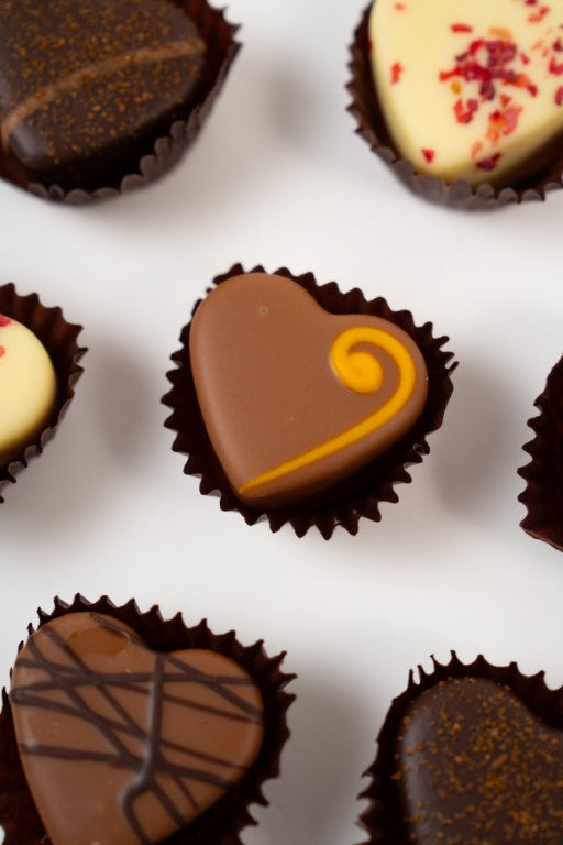 Gros plan sur un cœur truffe artisanal à la texture soyeuse et fondante.