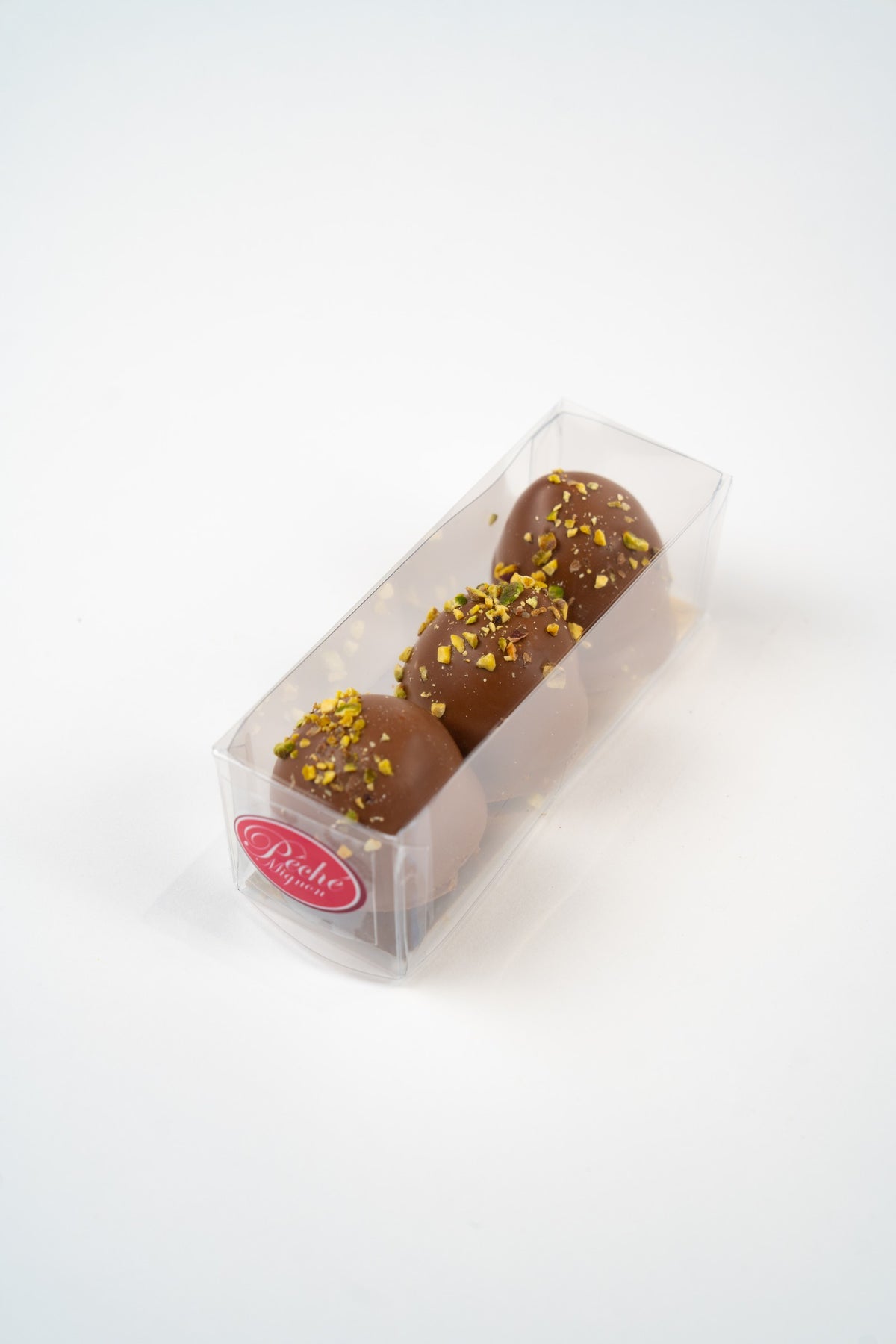 Doos met drie melocakes van melkchocolade, pistache en kadayif, gepresenteerd door Péché Mignon.