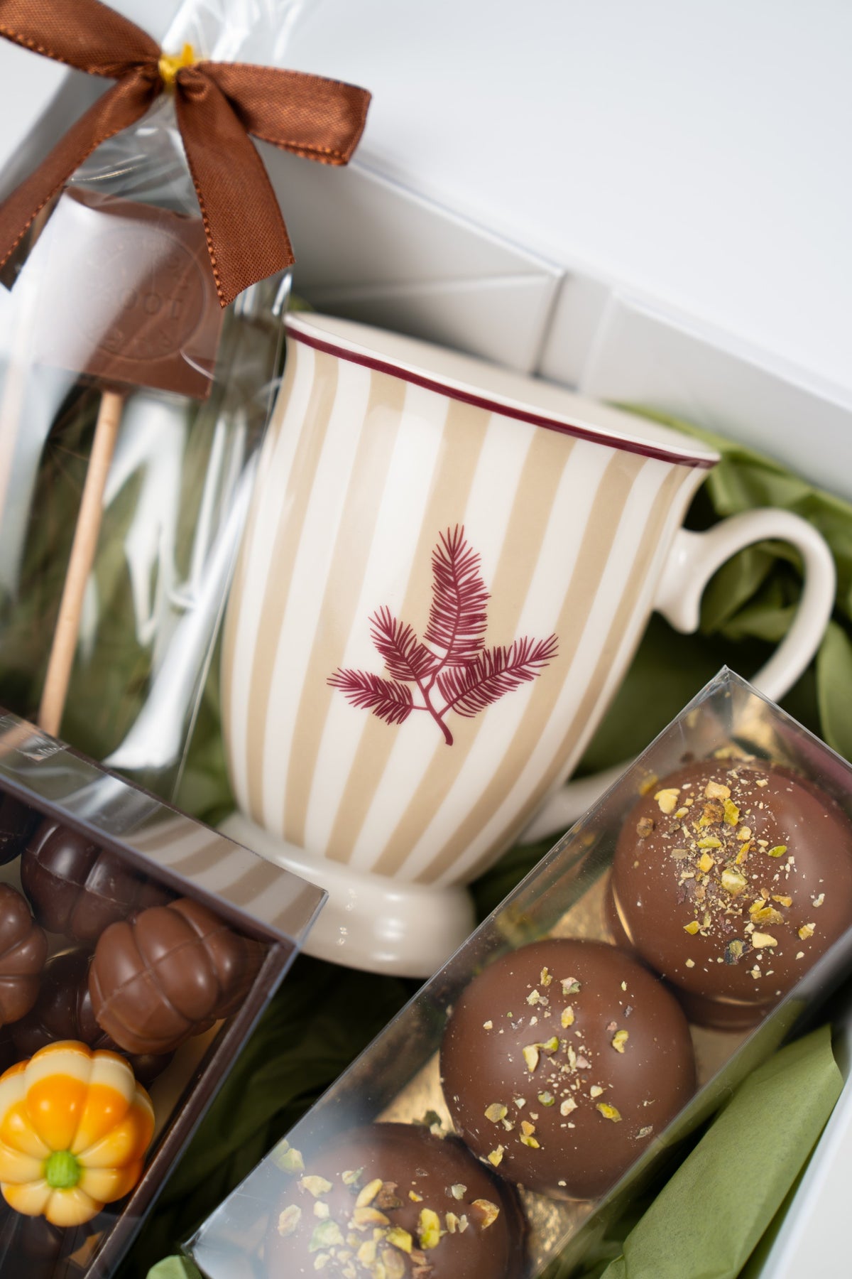 Beige-and-white striped Naemi mug with pumpkin-shaped chocolates and Dubai pistachio Melocakes in milk chocolate.