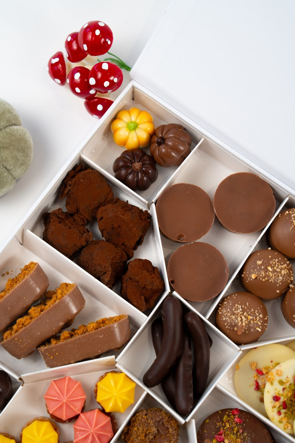 Close view of a Péché Mignon autumn gift box with cocoa-dusted truffles, pumpkin-shaped chocolates and milk chocolate discs.