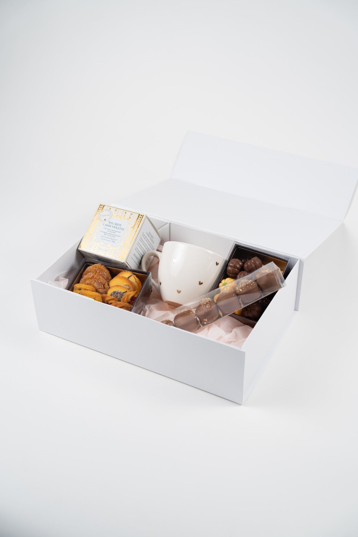 Open white autumn gift box with gold-heart mug, Dammann Frères tea, artisan biscuits and Belgian chocolates on pale pink tissue paper