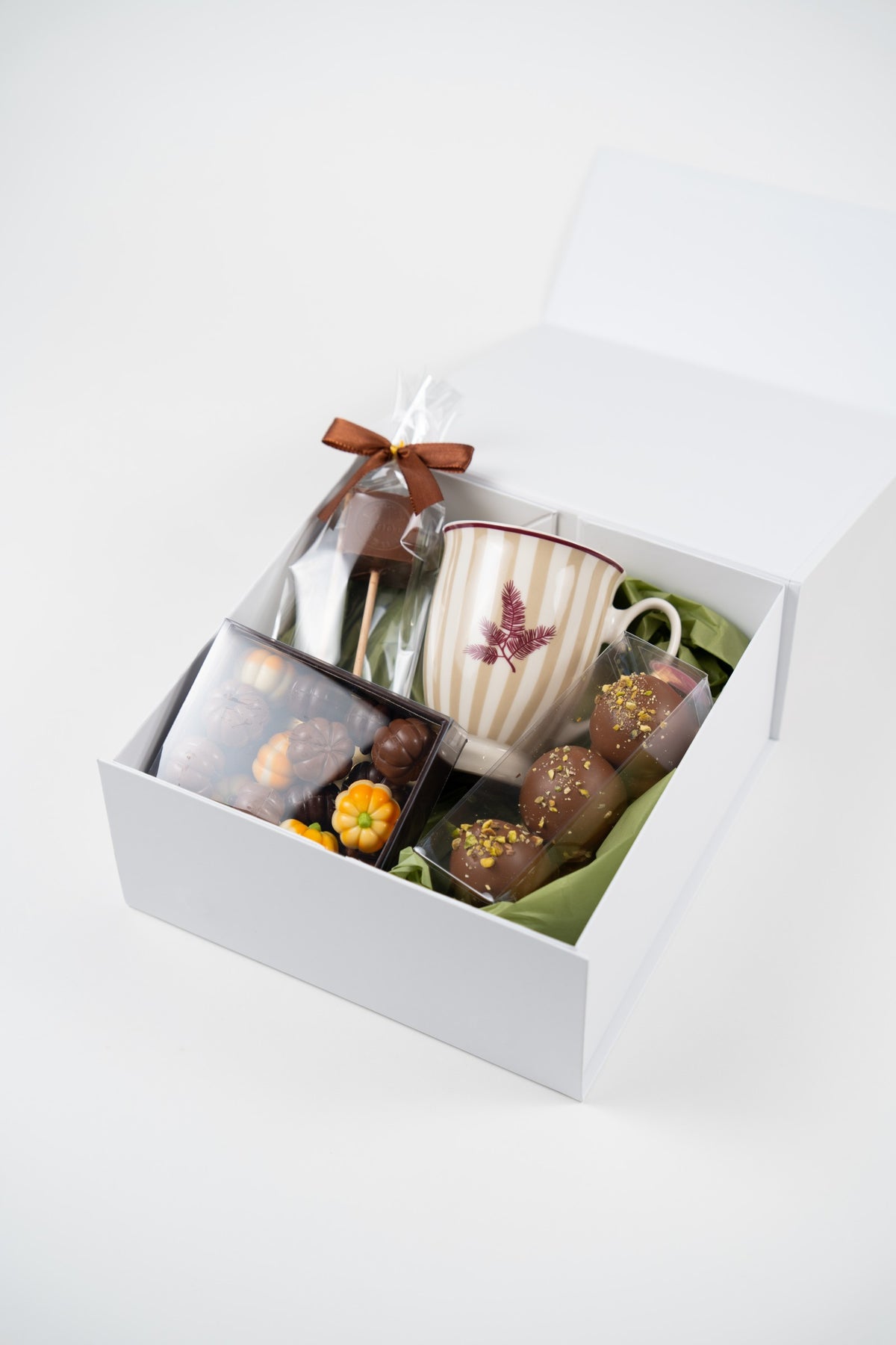 Open autumn hot chocolate gift box with Naemi mug, dark hot chocolate cubes, Dubai pistachio Melocakes and filled chocolate pumpkins.