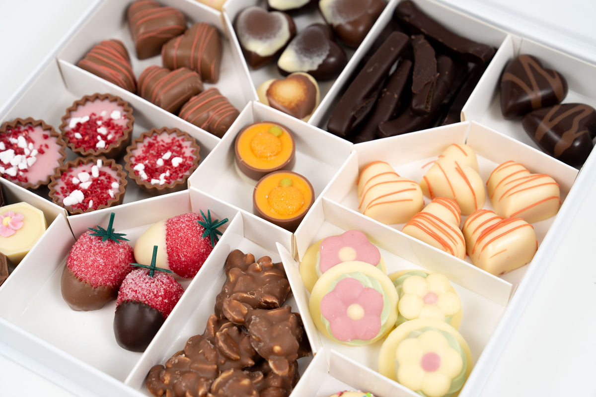Coffret de chocolats de printemps artisanal avec assortiment de pralinés, fraises enrobées, orangettes et chocolats fourrés