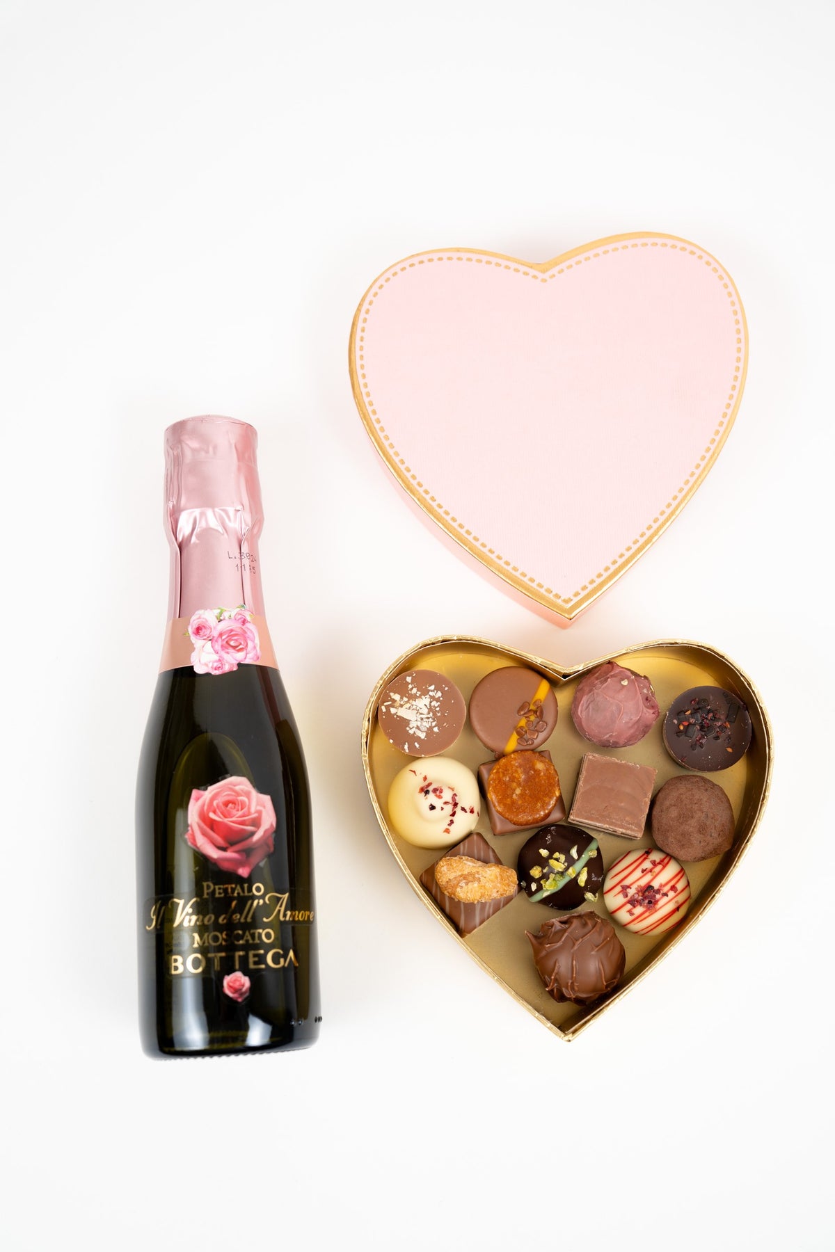 Coffret cœur rempli de pralines assorties accompagné d’une bouteille de Moscato rosé, cadeau gourmand élégant idéal pour une occasion romantique
