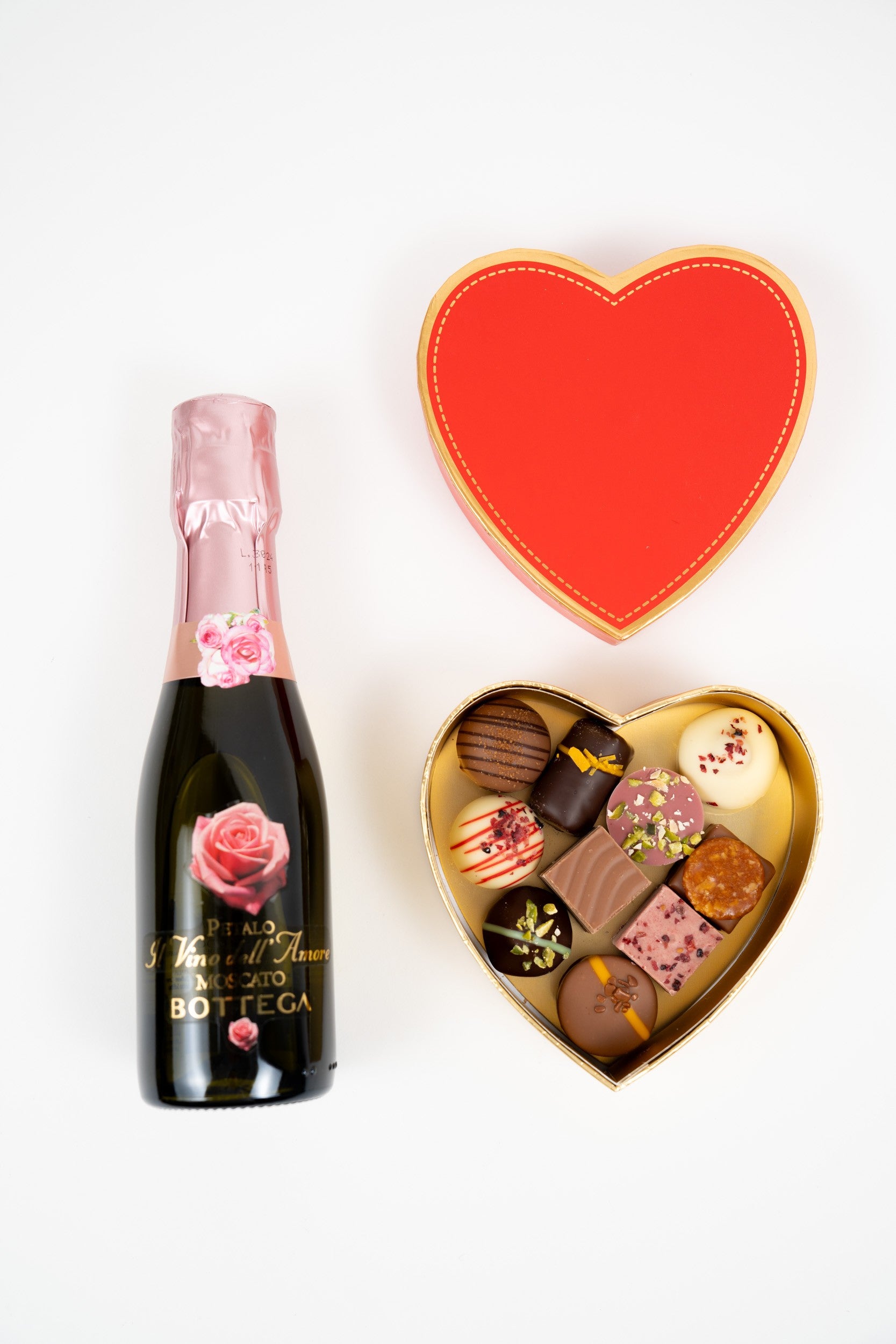 Coffret cadeau cœur rouge avec 110 g de pralines assorties et bouteille de Moscato rosé Péché Mignon