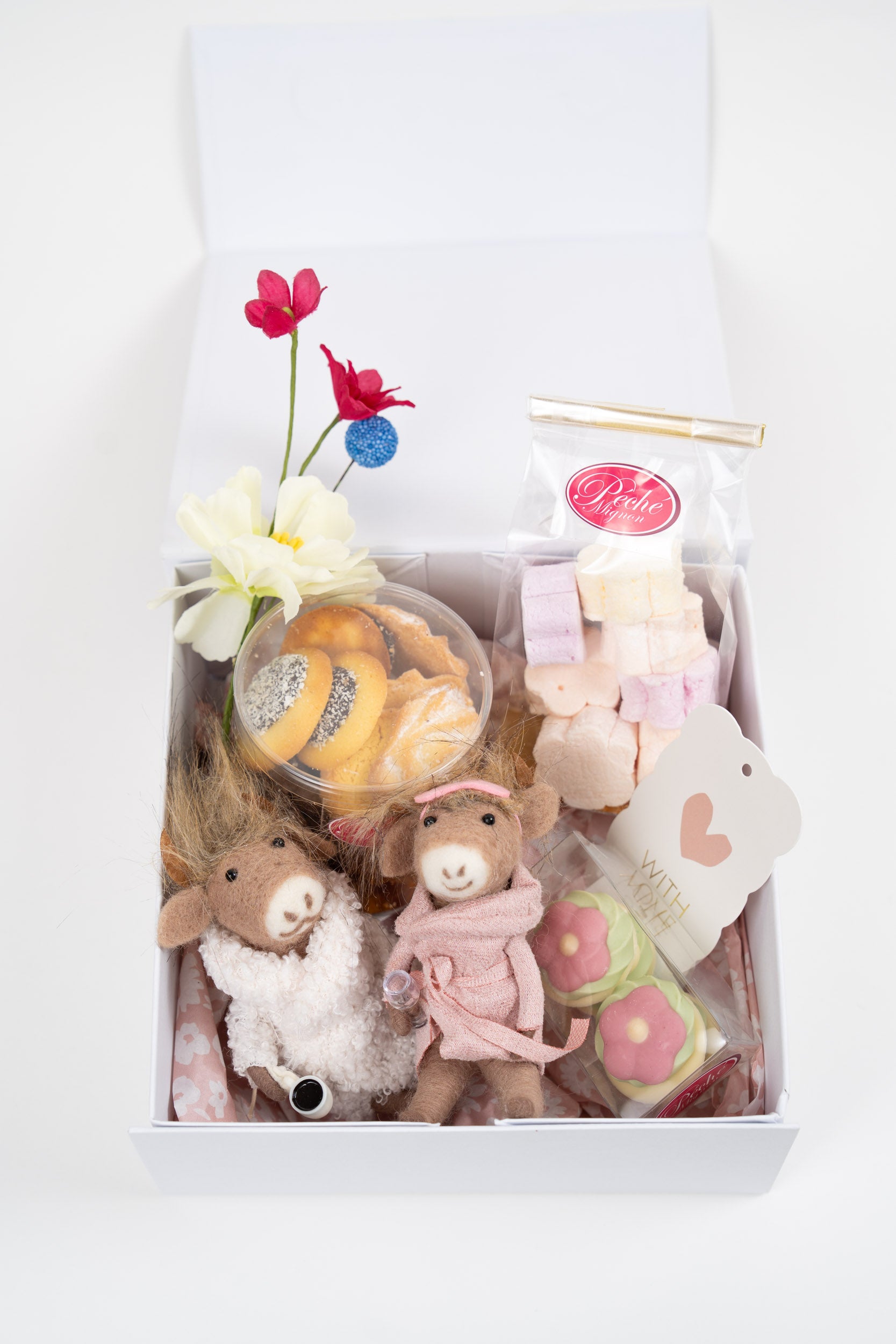 Coffret naissance fille Péché Mignon avec biscuits artisanaux, guimauves, fleurs décoratives et douceurs raffinées dans une élégante boîte cadeau.