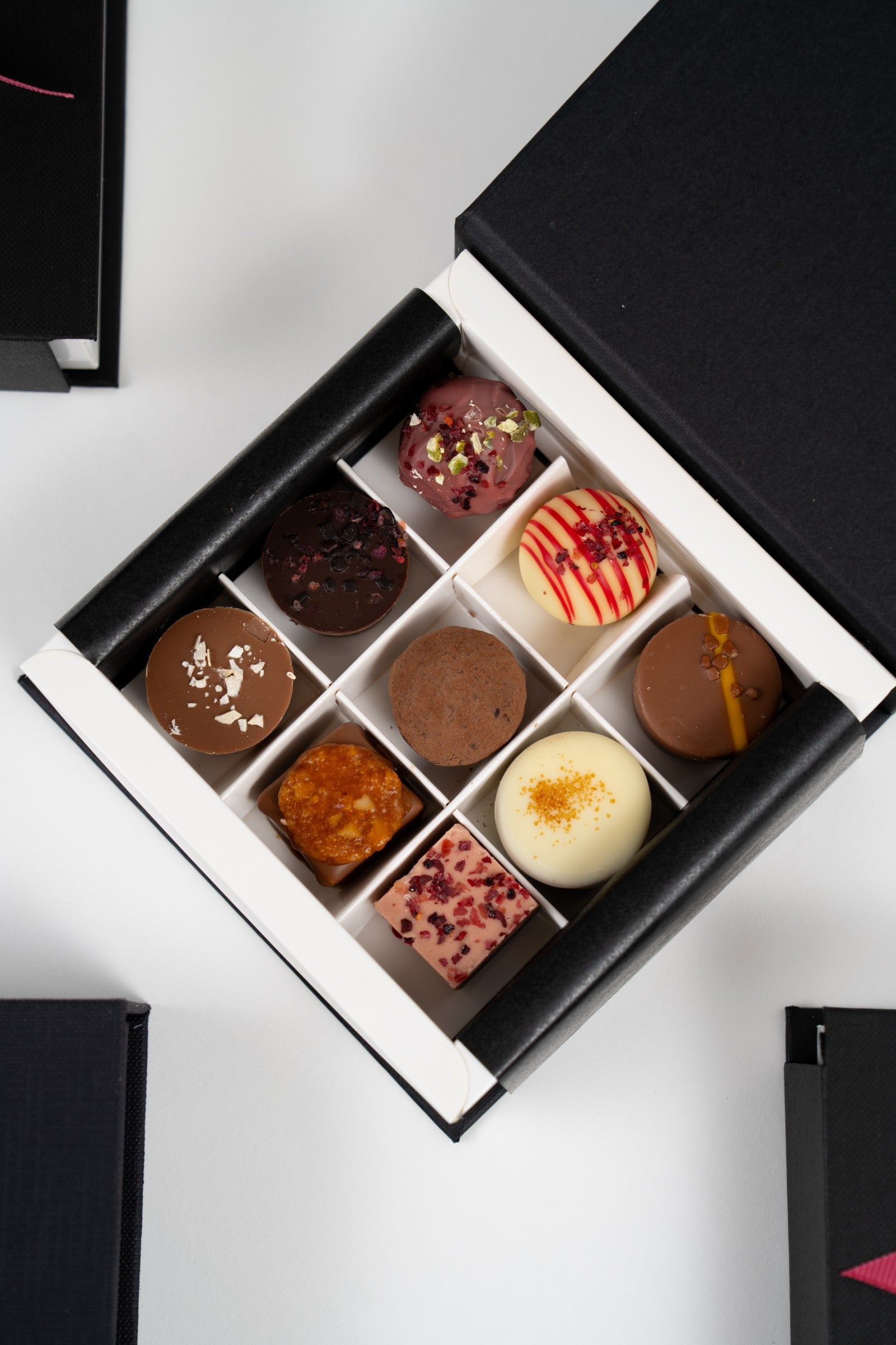 Vue rapprochée d’un coffret ouvert de pralines assorties Péché Mignon.